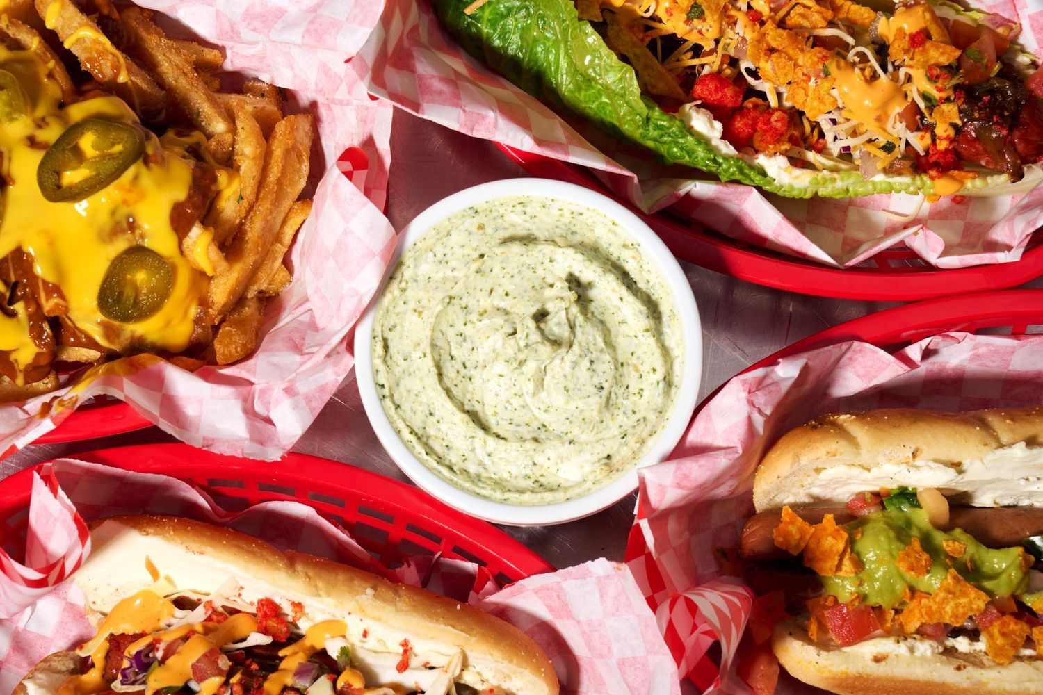Overhead restaurant food photo of hot dogs, loaded fries, and dip, styled for menu and social media.