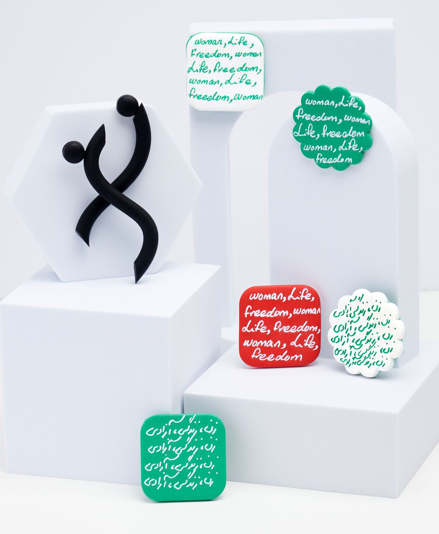 Handmade pins with Woman Life Freedom text, photographed for conceptual product and social impact branding.