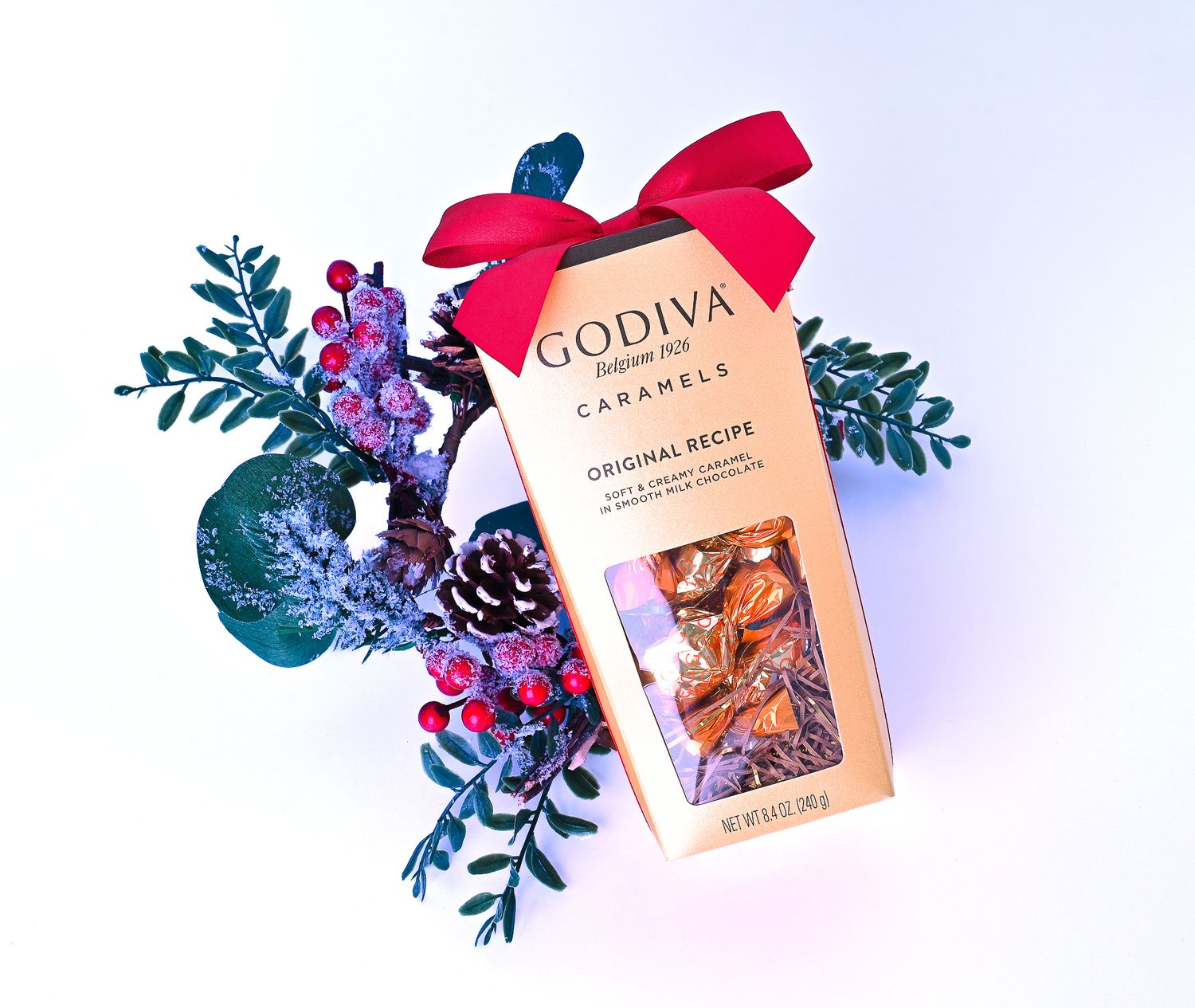 Godiva caramel gift box styled with winter greenery, photographed for holiday packaging and premium product branding.