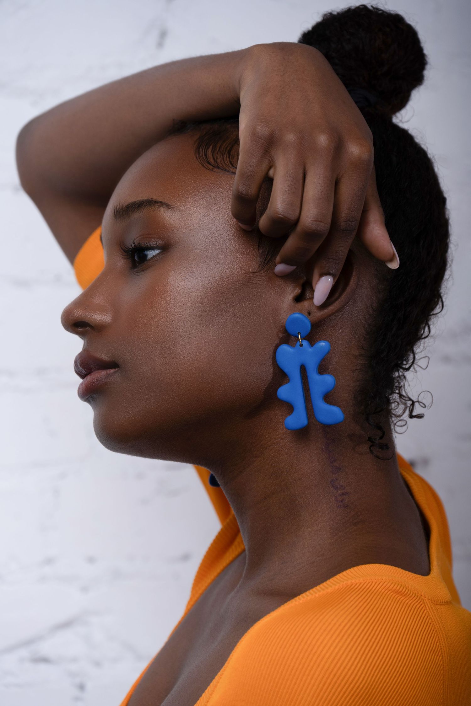 Close-up beauty portrait highlighting bold blue statement earrings and clean studio lighting.