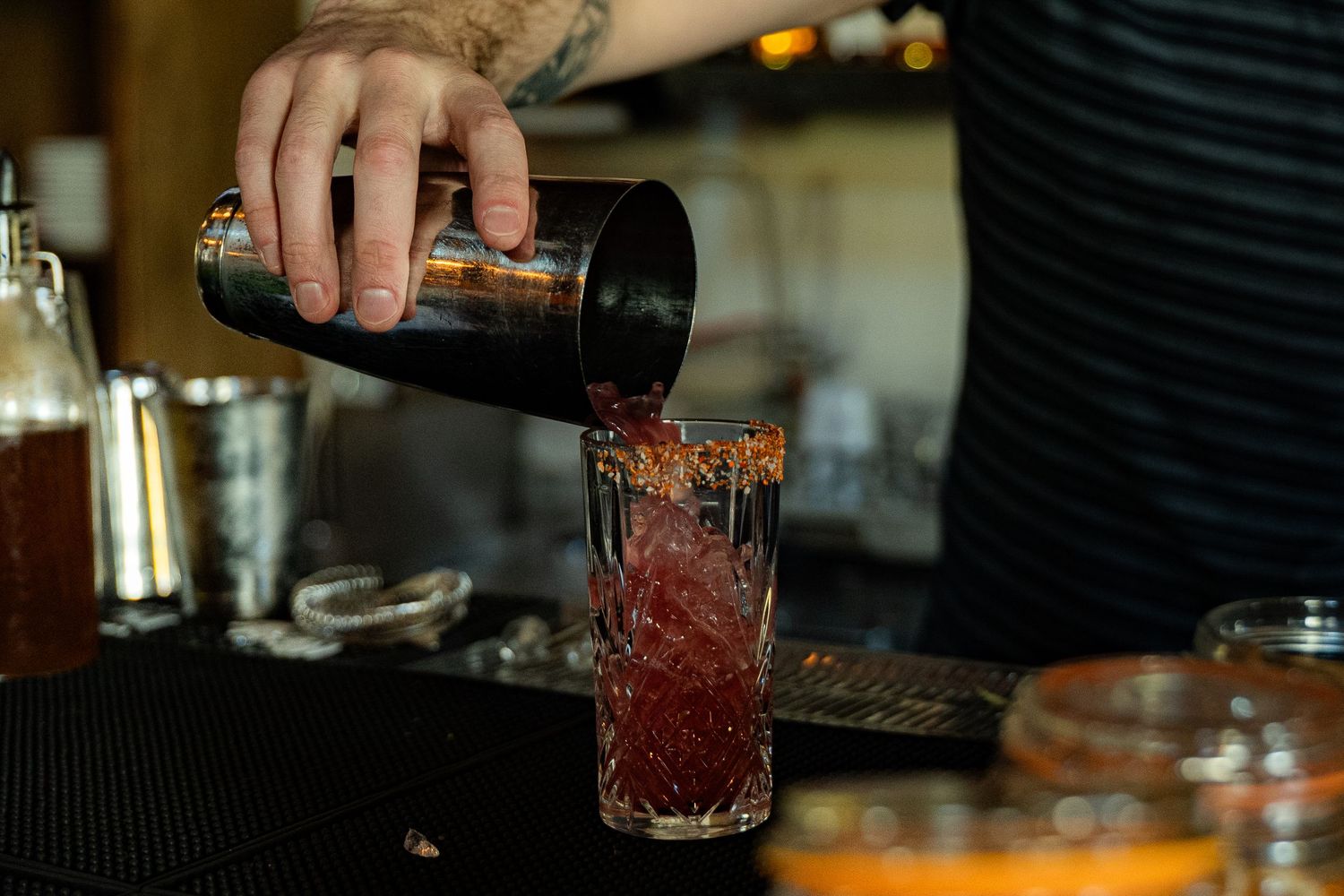 Bartender pouring cocktail into glass, photographed for bar menu, beverage branding, and hospitality marketing.