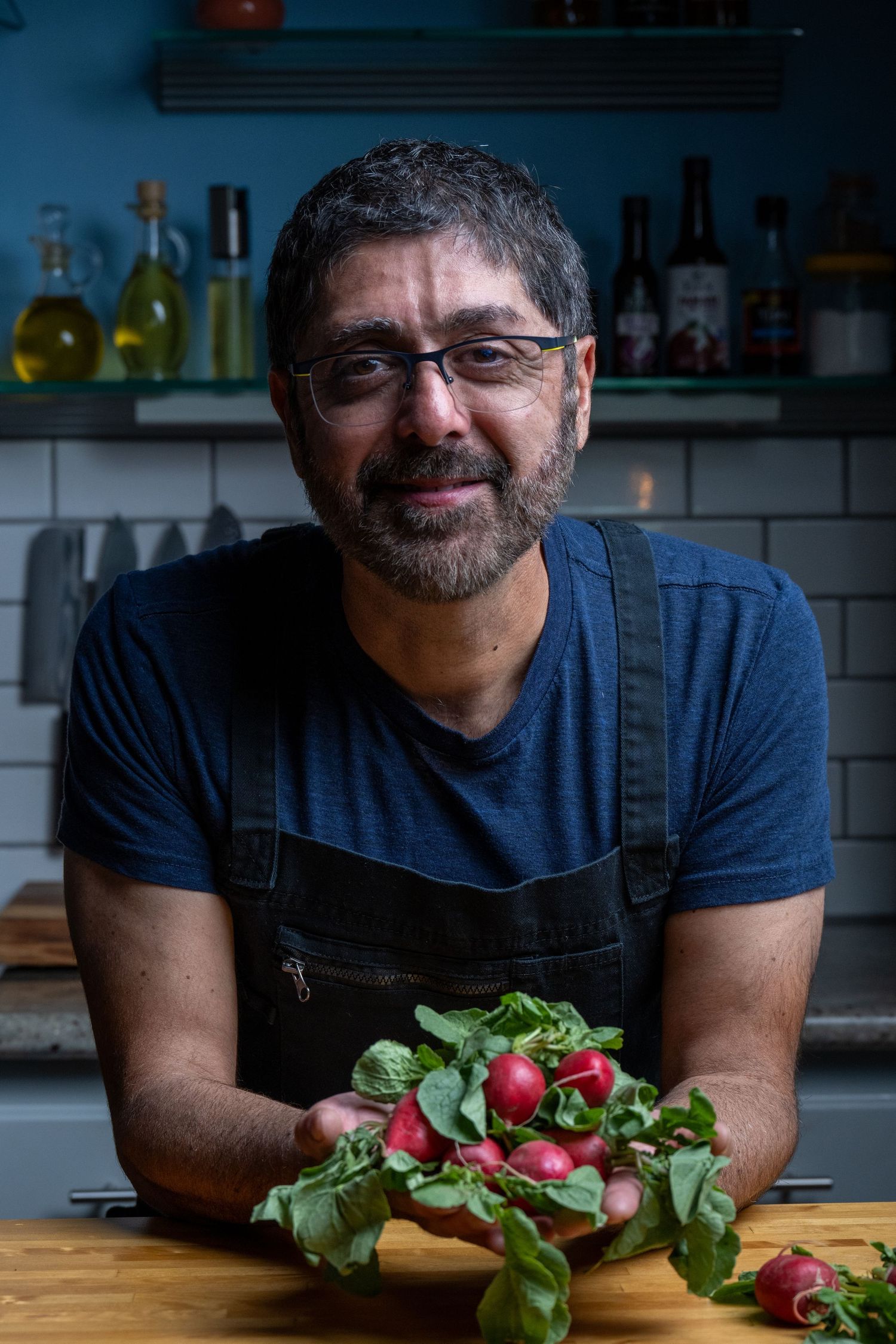 Moody culinary portrait with fresh produce and layered kitchen backdrop. Story-driven and atmospheric.