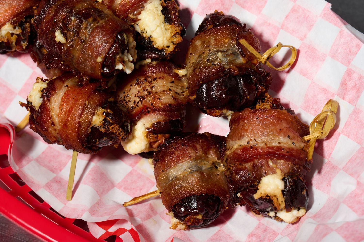 Bacon-wrapped stuffed dates photographed with dramatic lighting for restaurant appetizer menu photography.