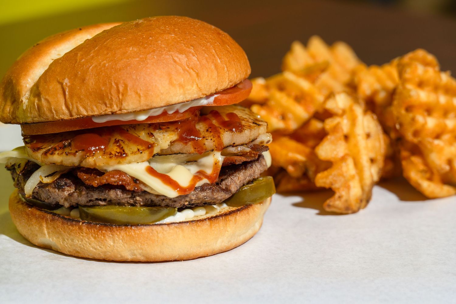 Burger and waffle fries styled in warm lighting for restaurant marketing and menu photography.