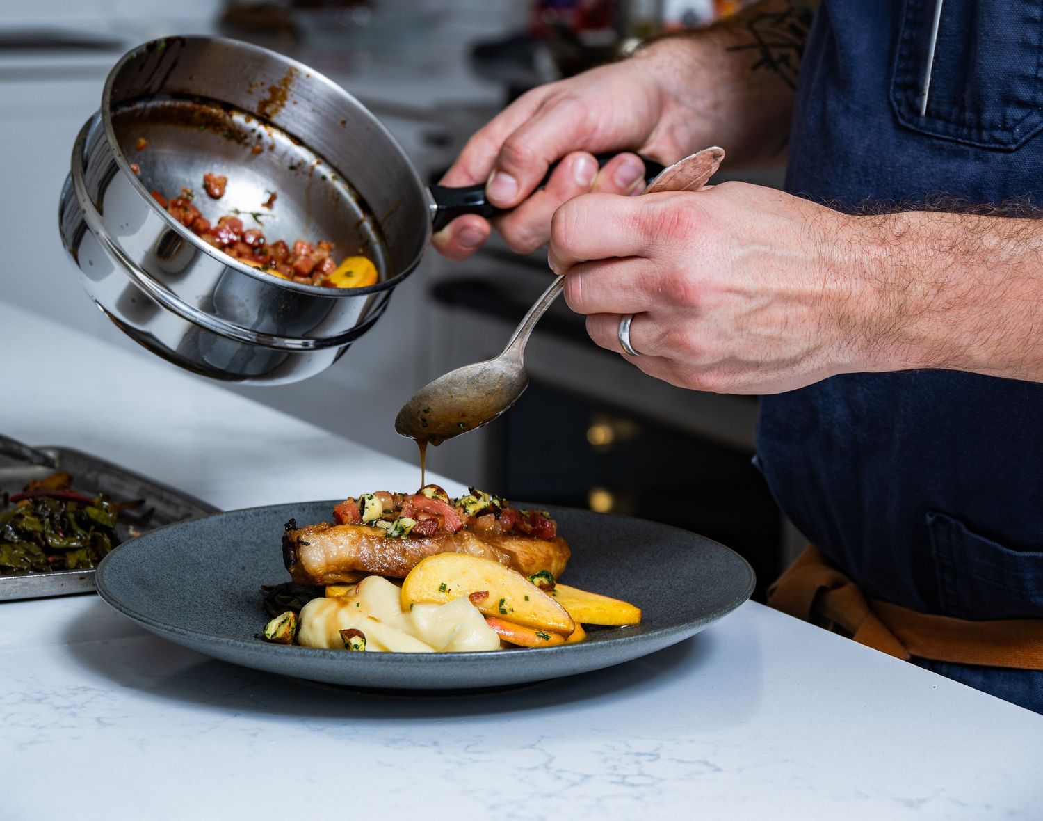 Chef finishing plated entrée with sauce, photographed for restaurant branding and commercial food photography.
