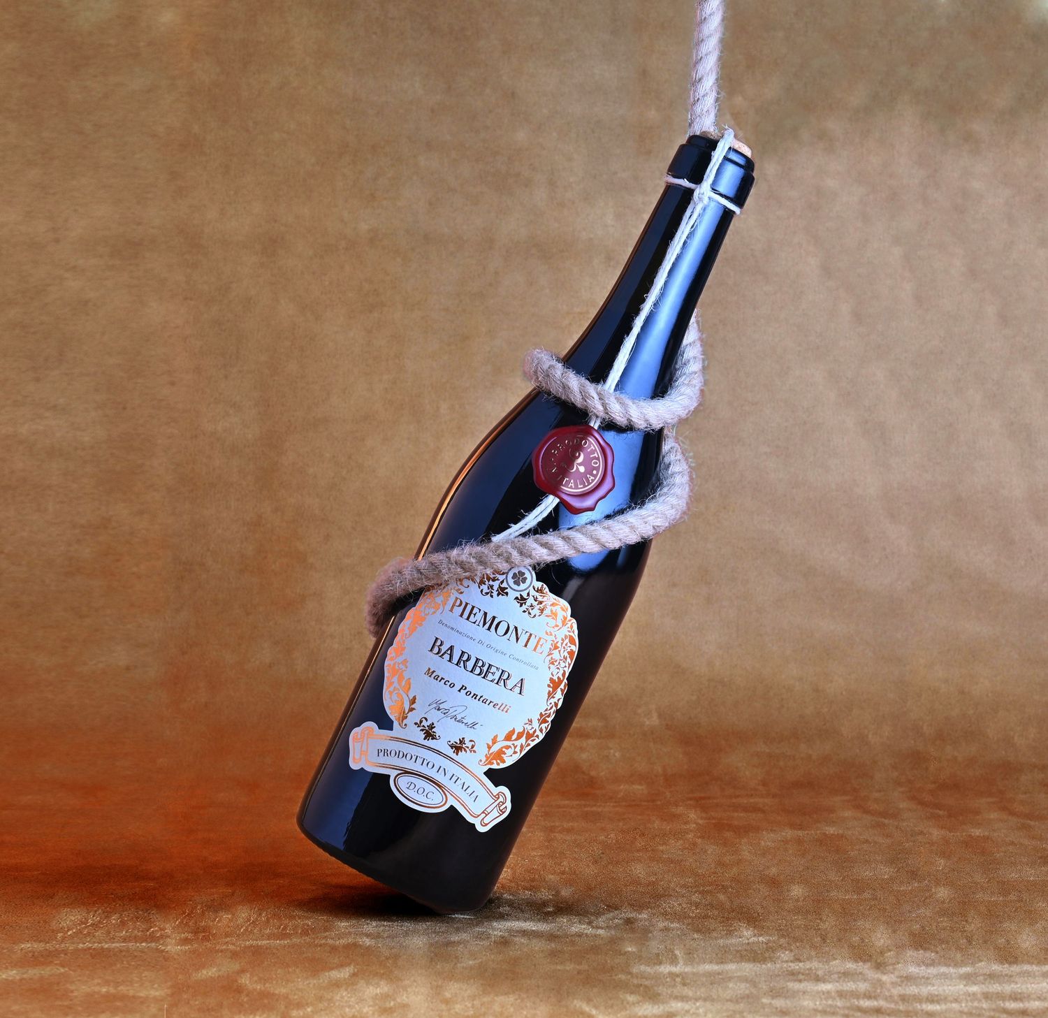 Wine bottle product shot styled with rope against warm textured backdrop for a refined, editorial look.