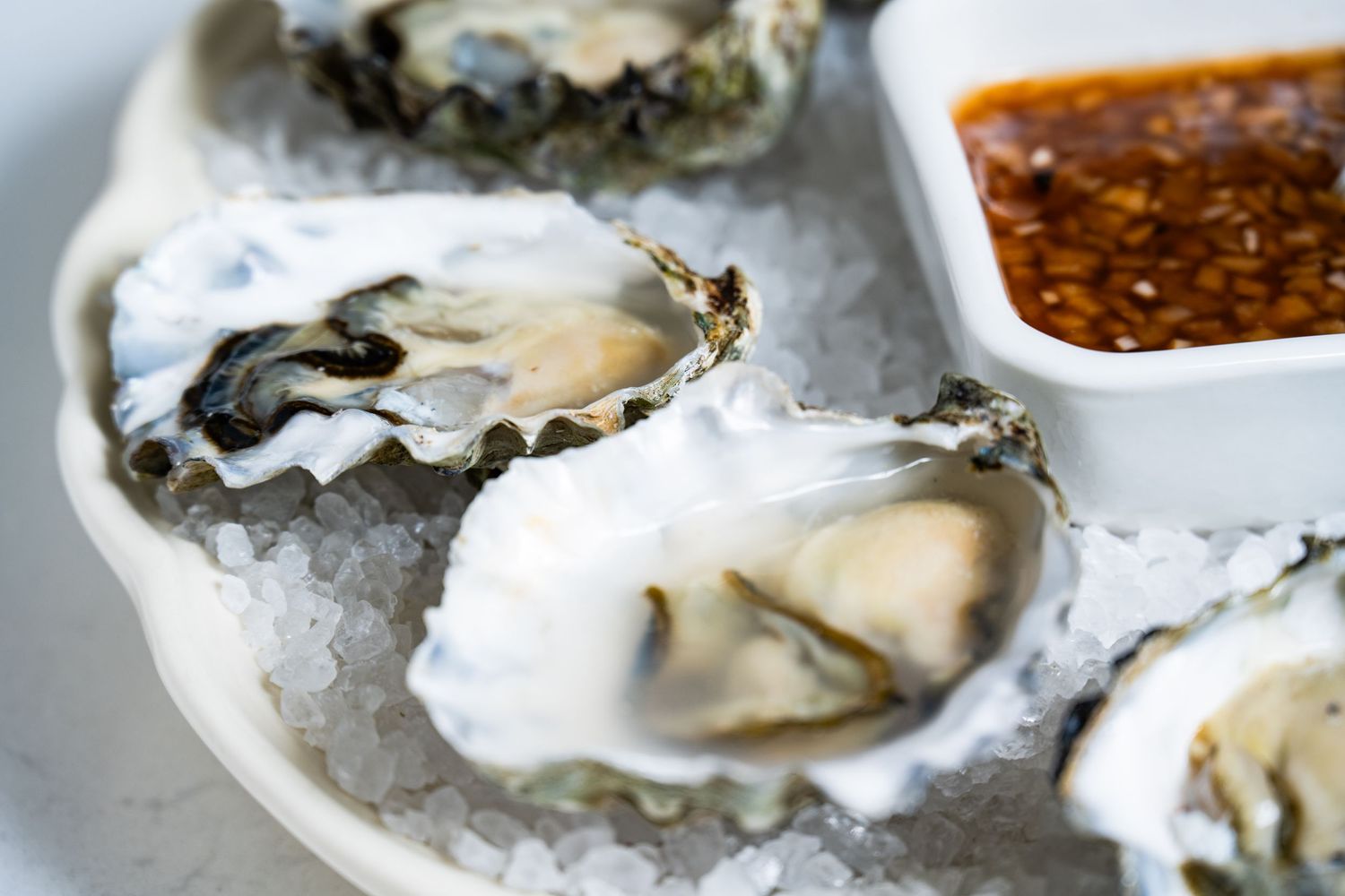 Fresh oysters on ice with dipping sauce, photographed for seafood menu and restaurant food photography.