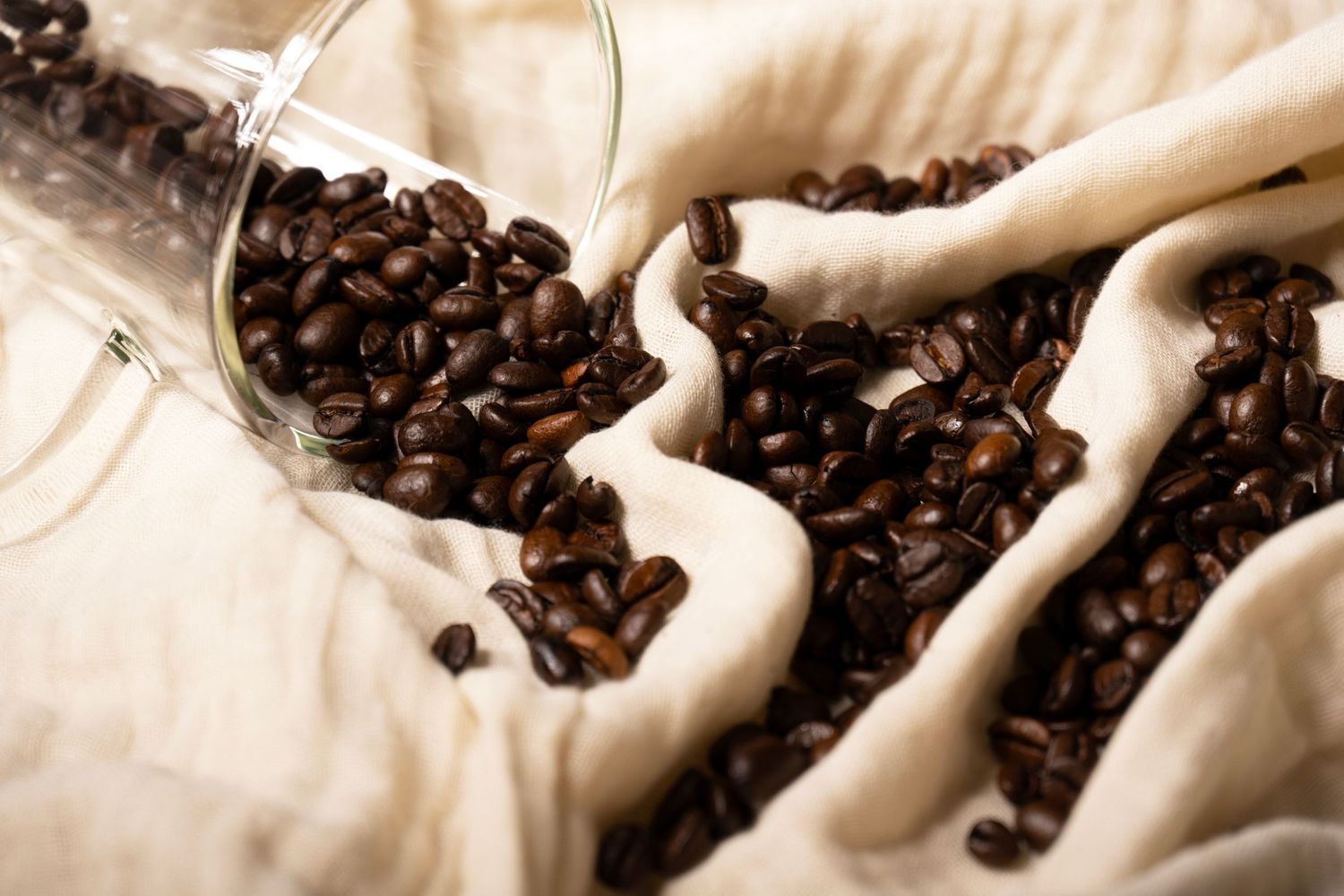 Roasted coffee beans styled on textured fabric, photographed for café branding, packaging, and commercial use.