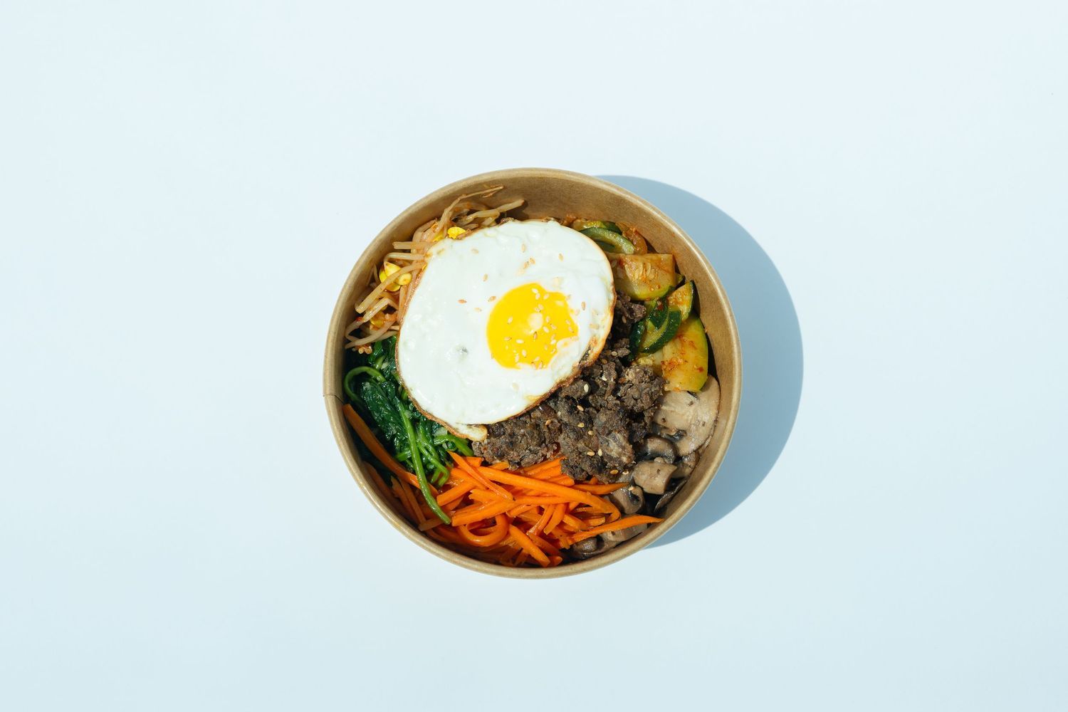 Korean bibimbap bowl with fried egg and vegetables, photographed for restaurant menu and commercial food photography.
