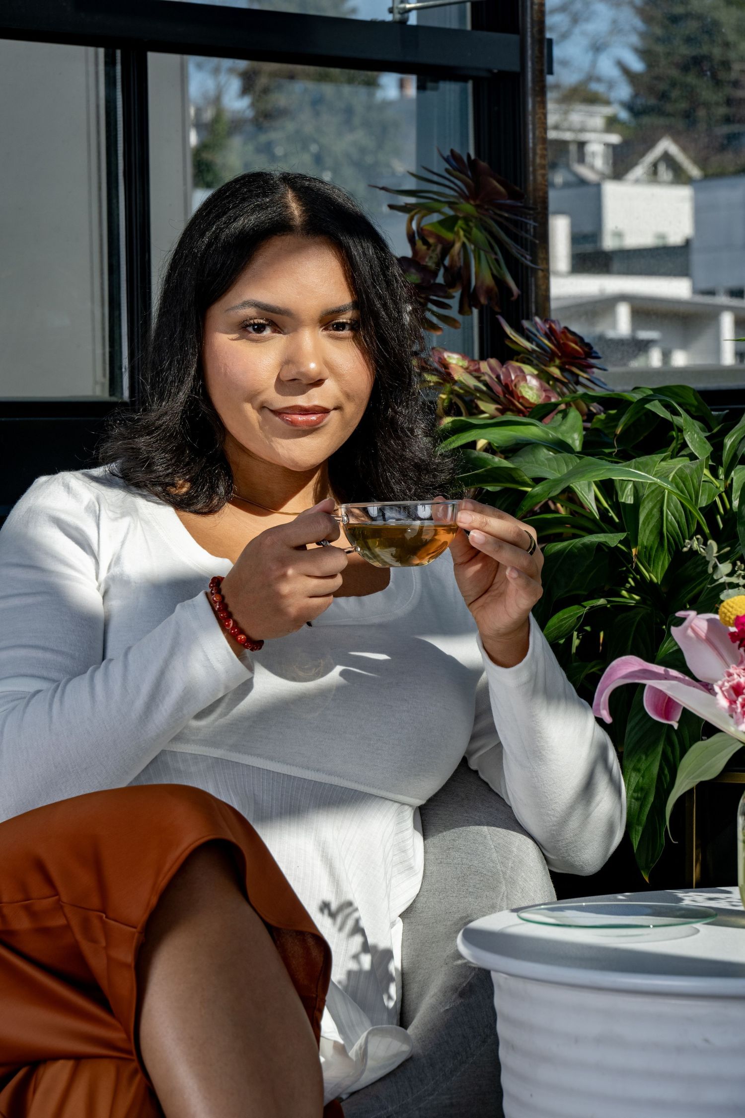 Lifestyle branding portrait of woman holding tea in sunlit studio, photographed for wellness and personal brand imagery.