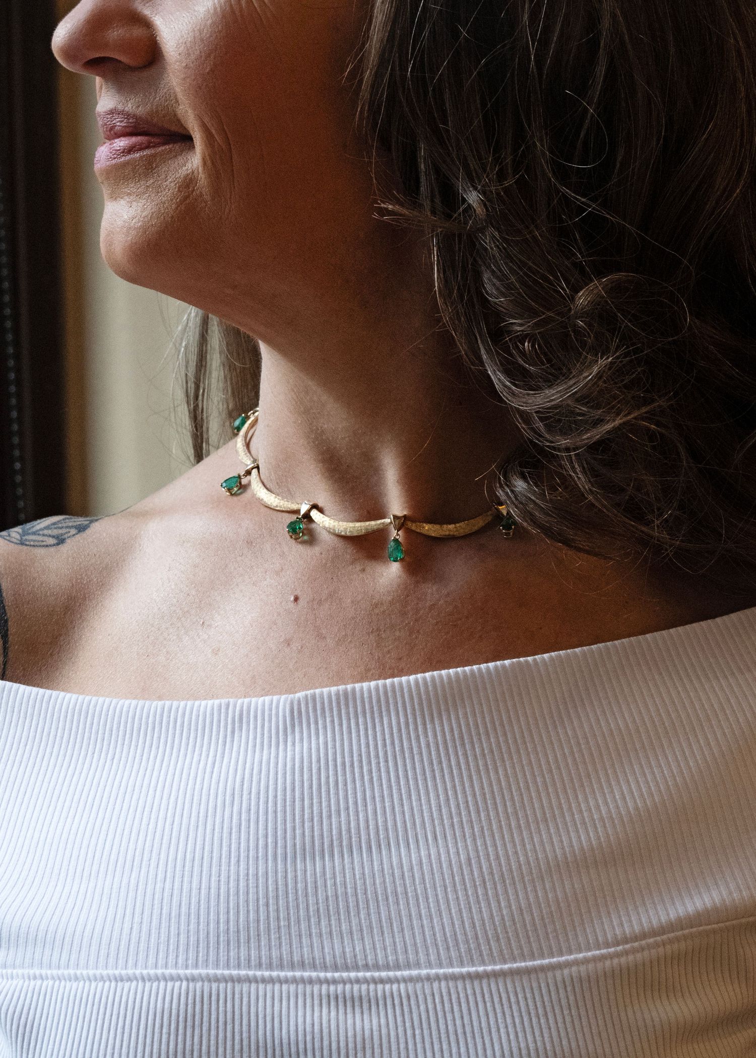 Emerald drop necklace worn on model in soft window light, capturing natural texture and timeless elegance.