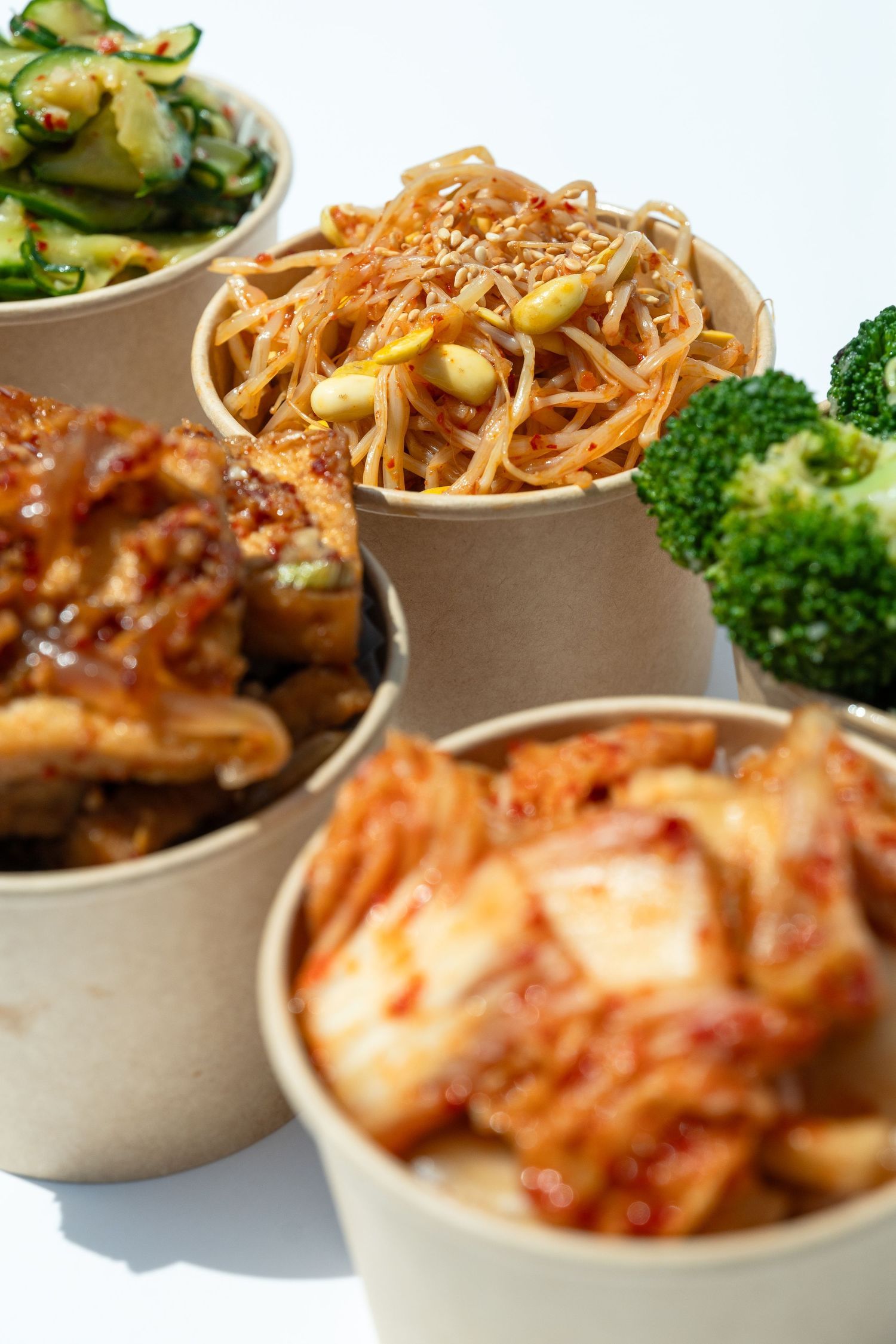 Korean banchan side dishes in takeout containers, photographed for restaurant menu and commercial food use.