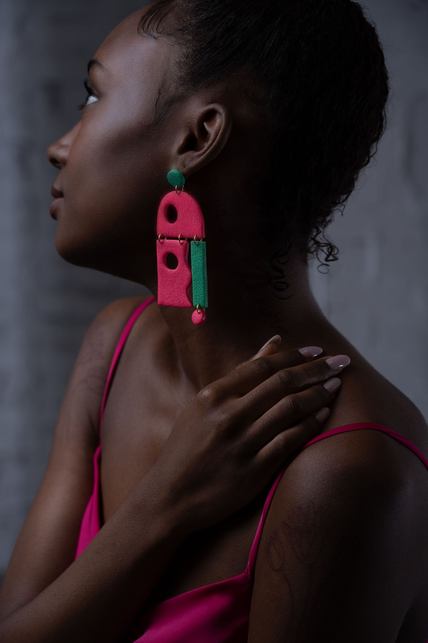 Studio portrait of woman wearing bold handmade statement earrings in dramatic fashion lighting.