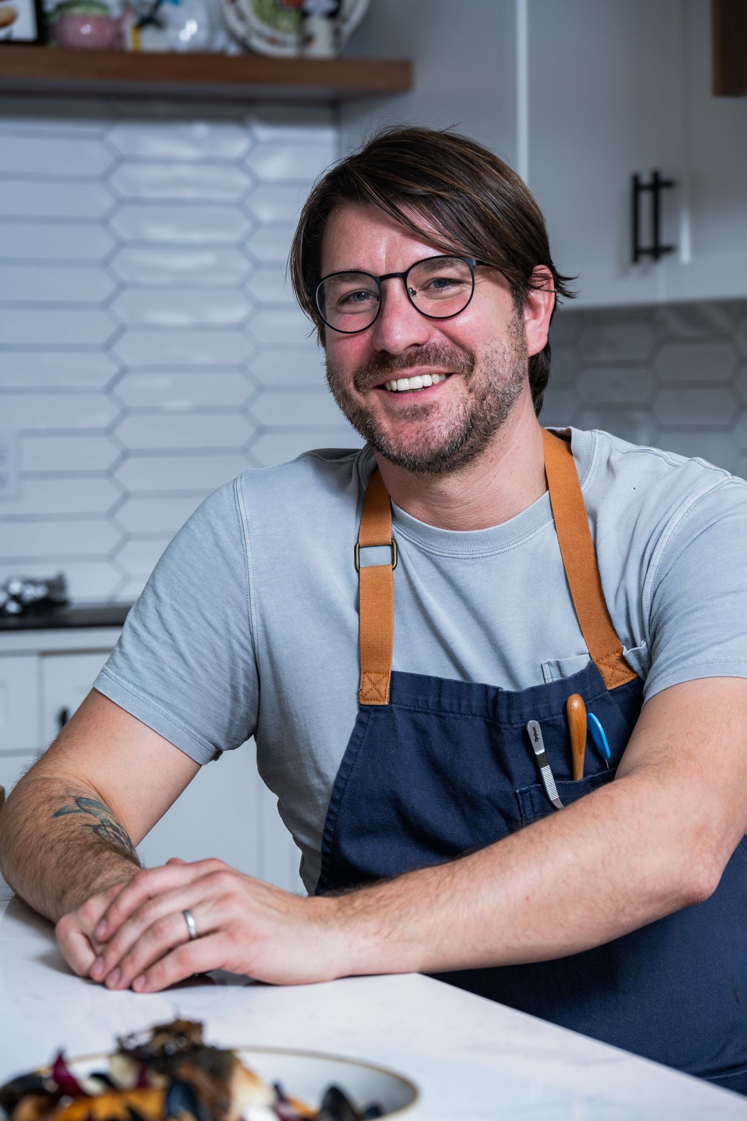 Casual chef portrait in bright kitchen light. Genuine, relaxed, and brand-forward.