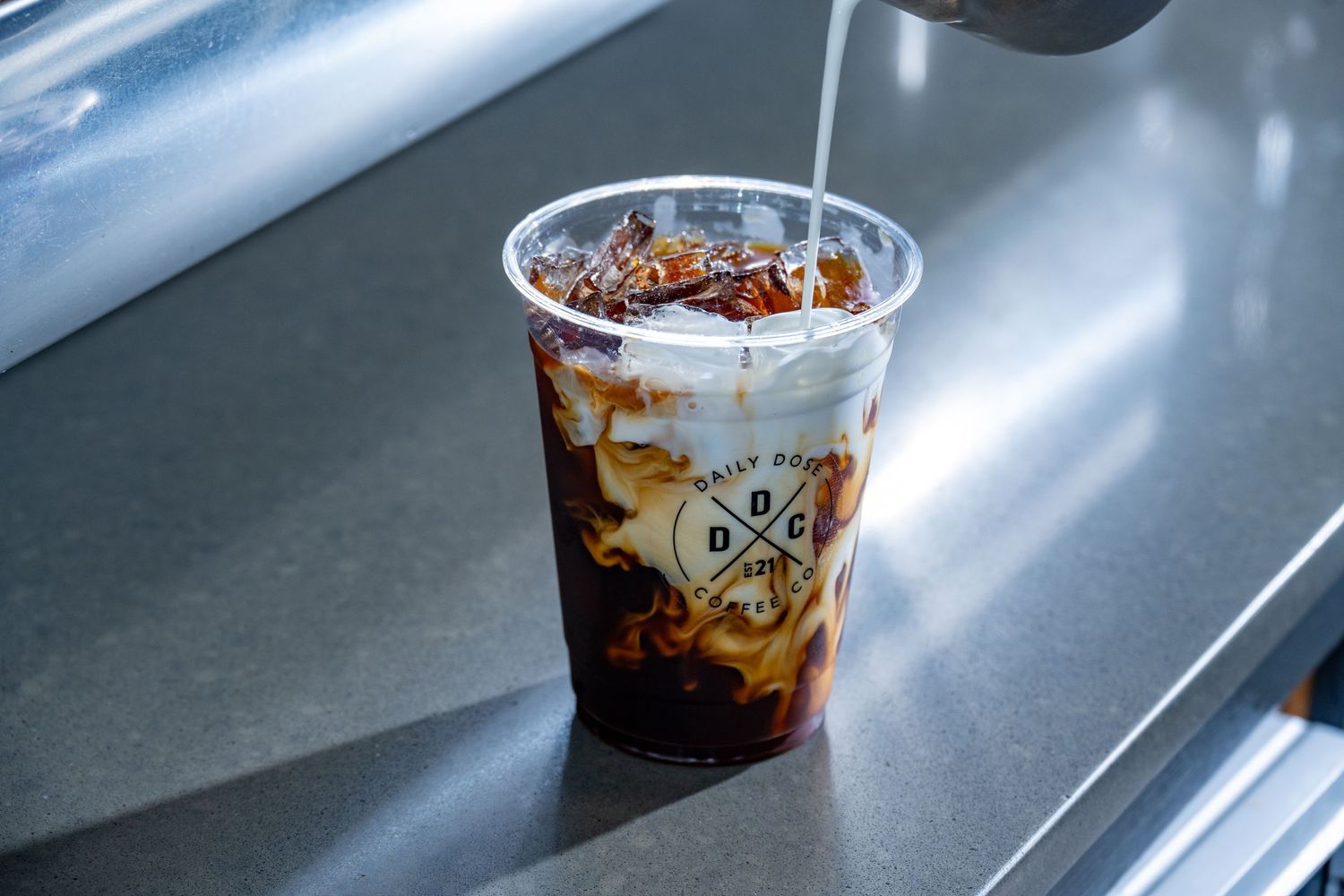 Clean, modern product photo of iced coffee with cream swirl in a clear cup—perfect for café branding, menus, and social media.
