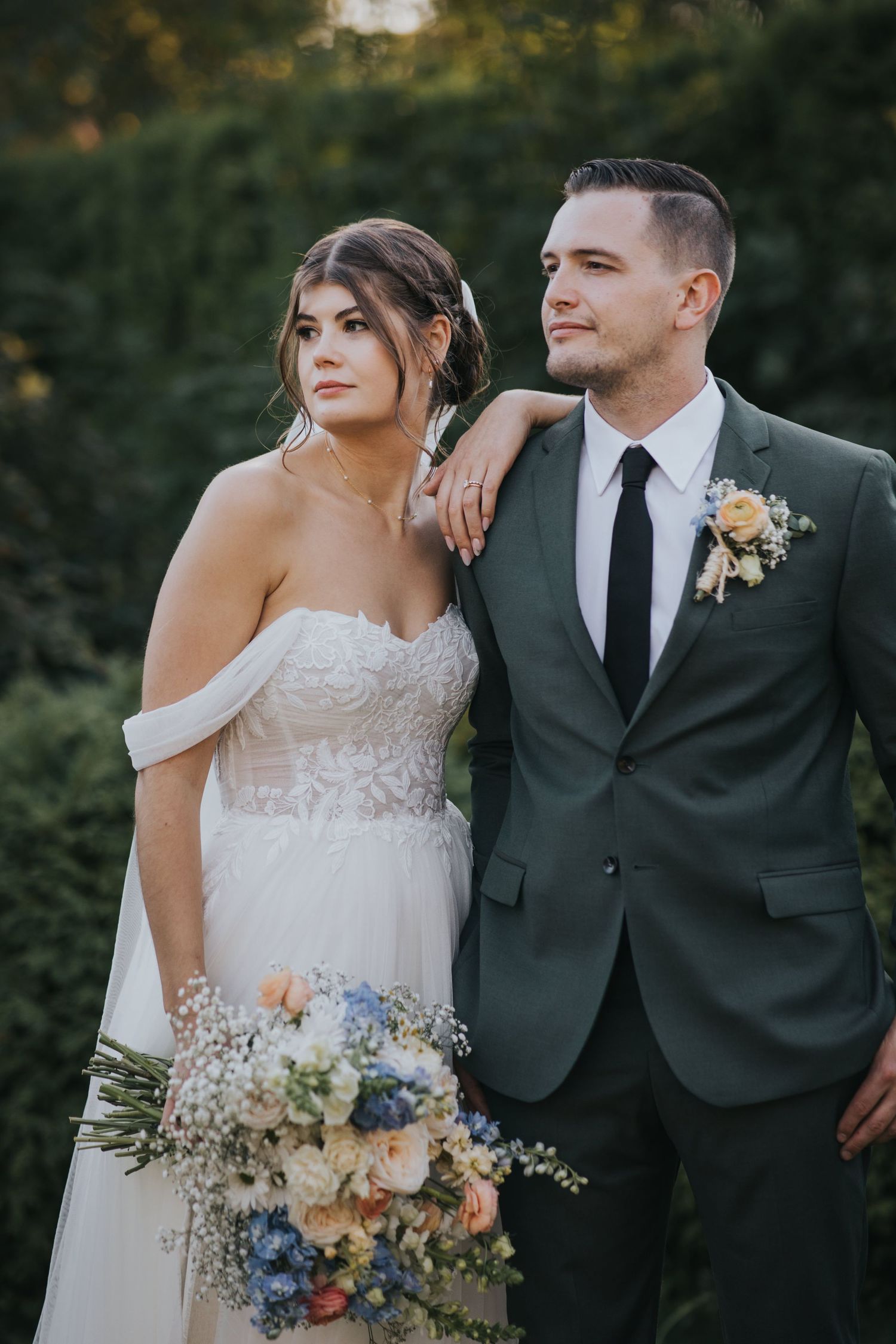 Editorial portrait of the bride resting her hand on the groom's shoulder in the garden