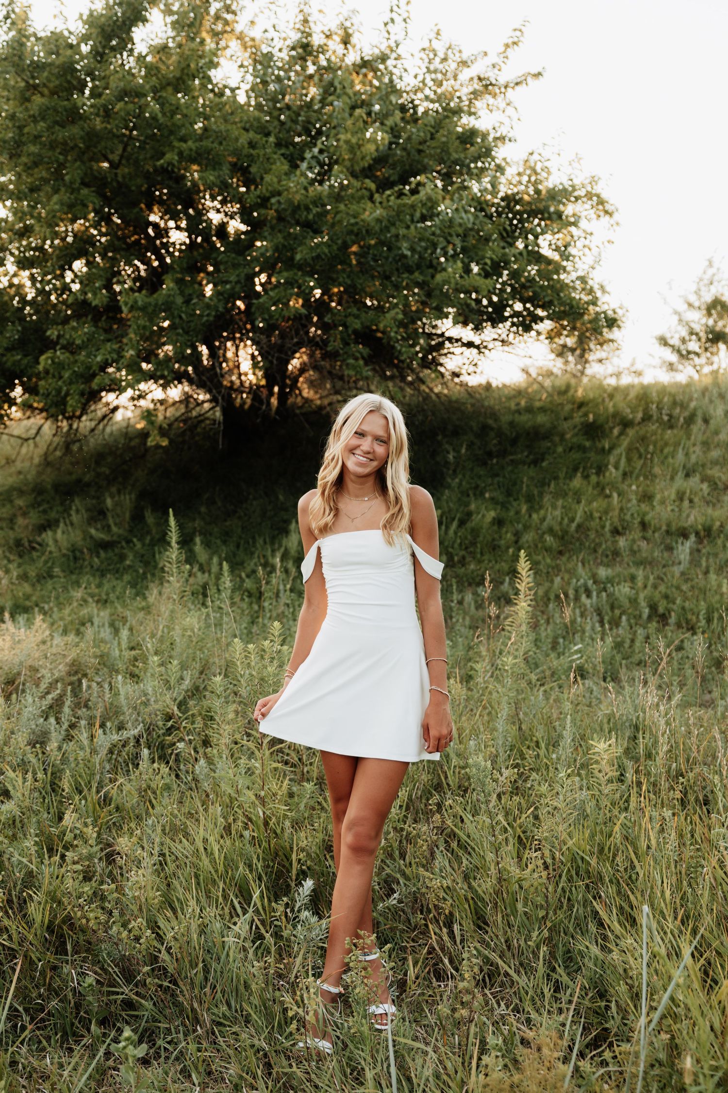 Summer portraits in white dress against natural grassland backdrop.