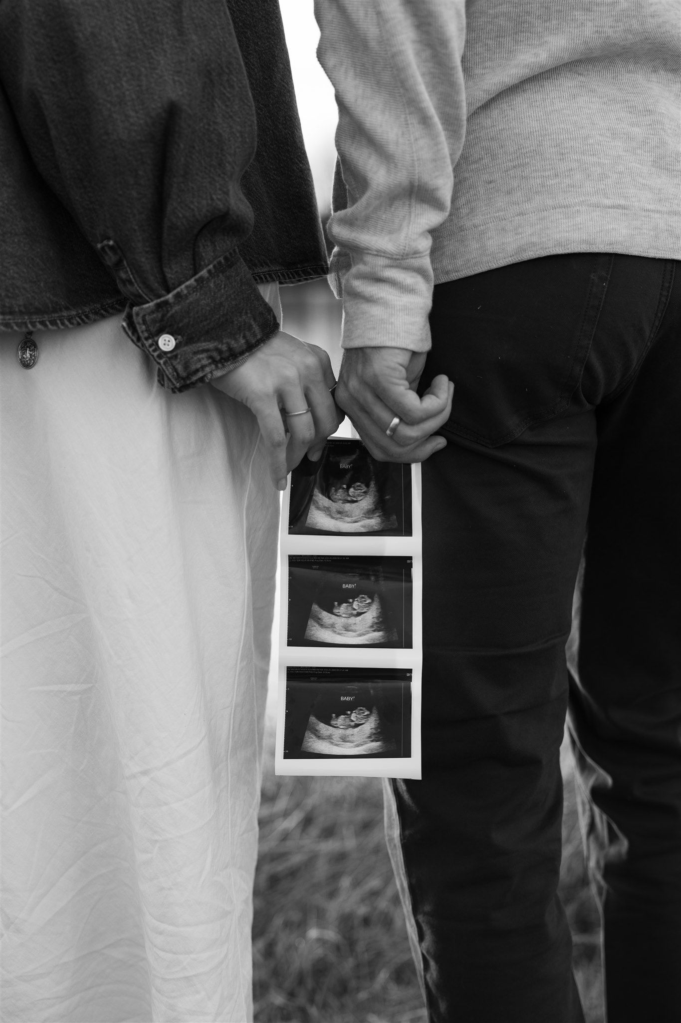 Black and white photo of couple holding ultrasound photos, pregnancy announcement, maternity shoot.