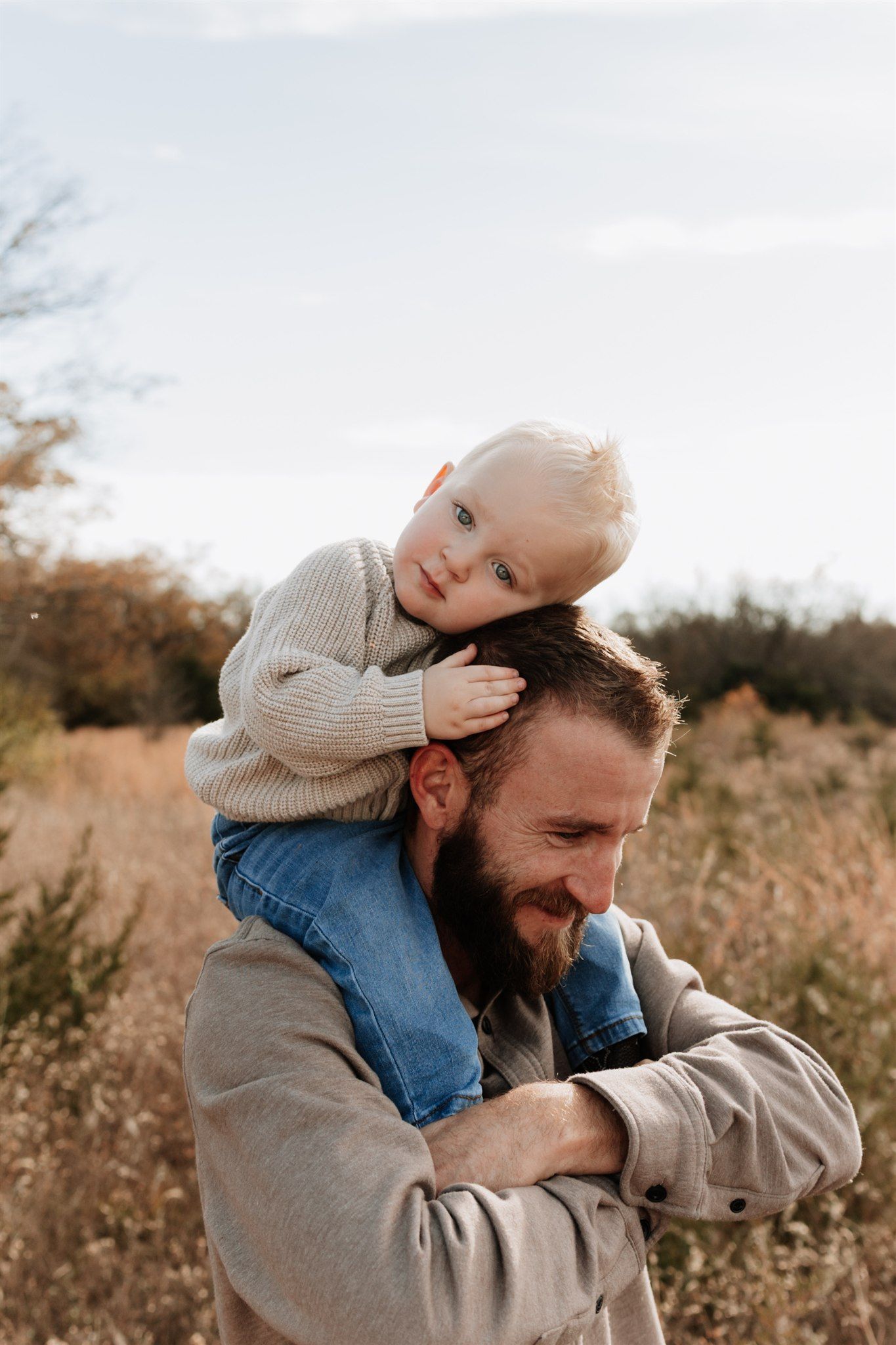 Playful moments between parent and child in outdoor field during golden hour.