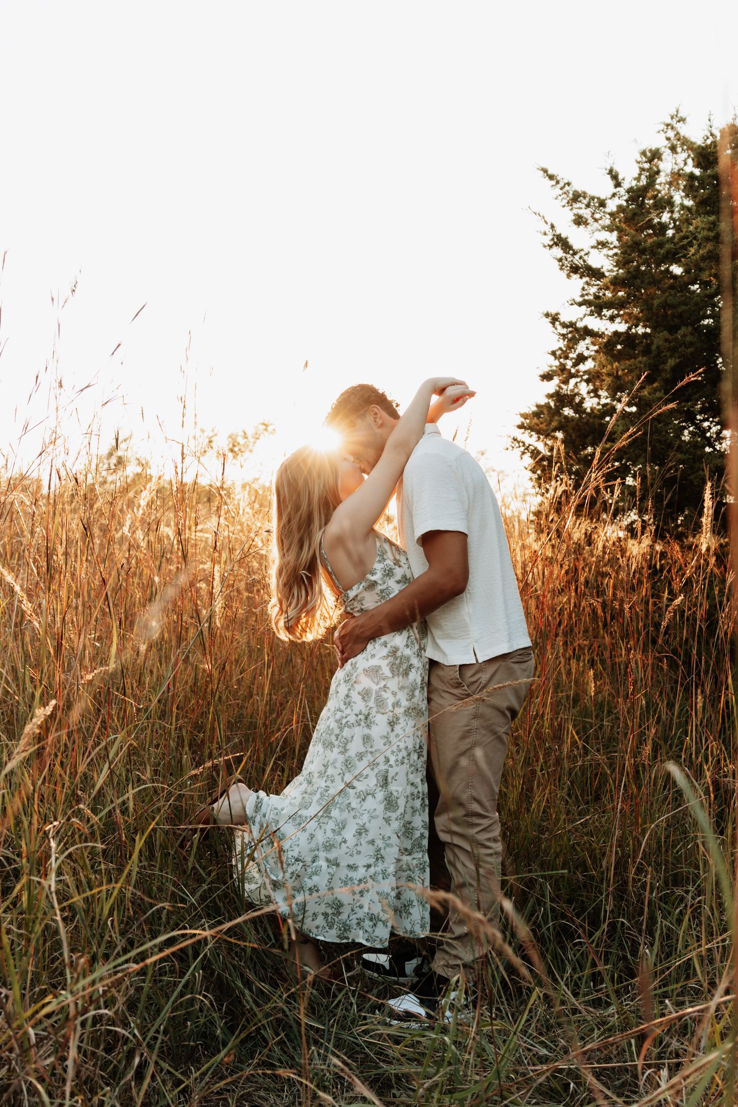 A couple sharing intimate moments in a golden wheat field at sunset.