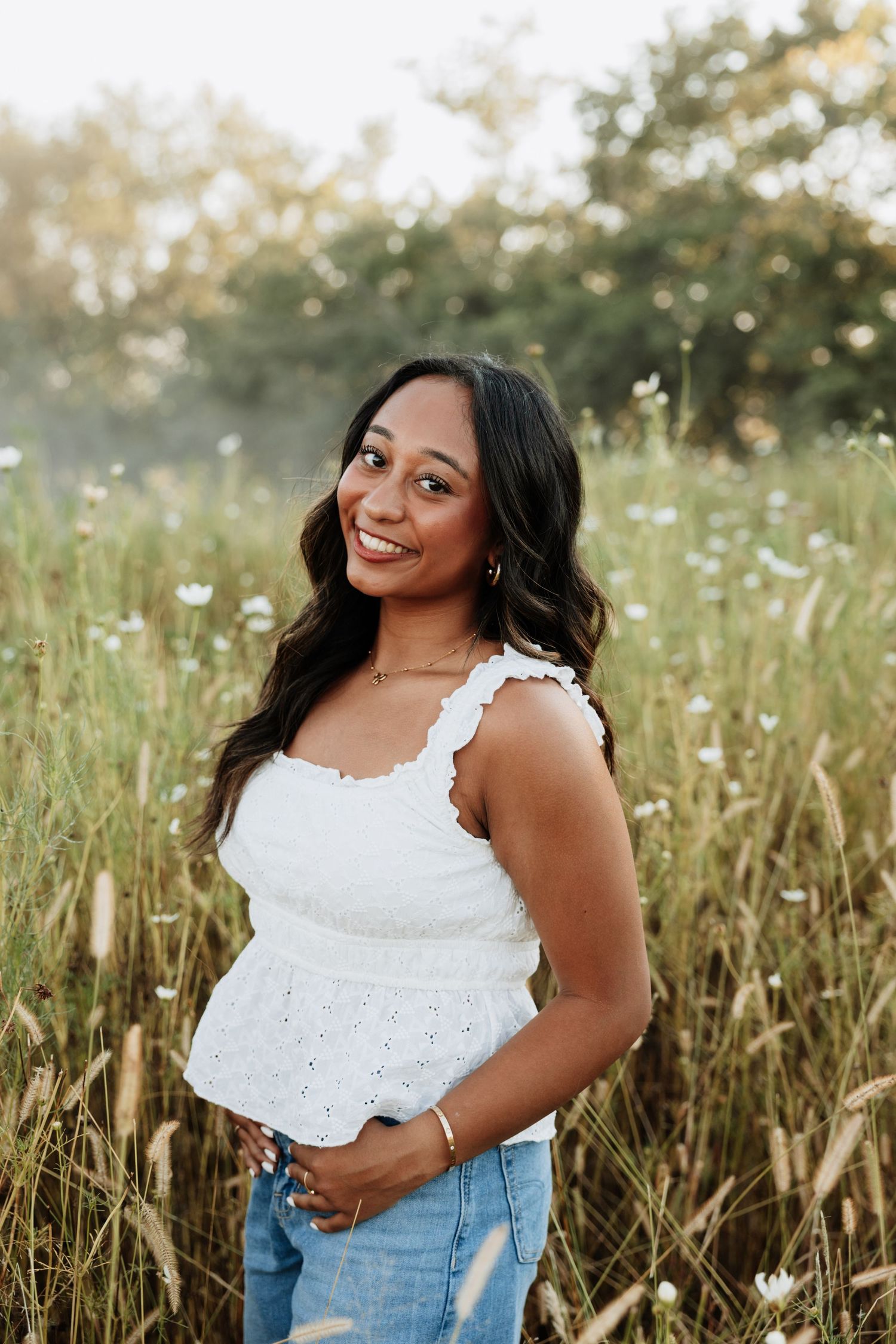 Summer portrait session in field with white eyelet top and denim.