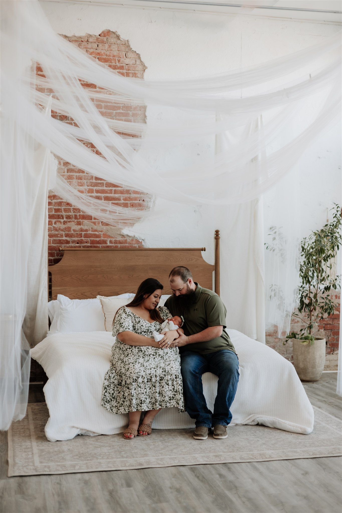 Intimate couple photo session with white drapes and exposed brick wall backdrop.