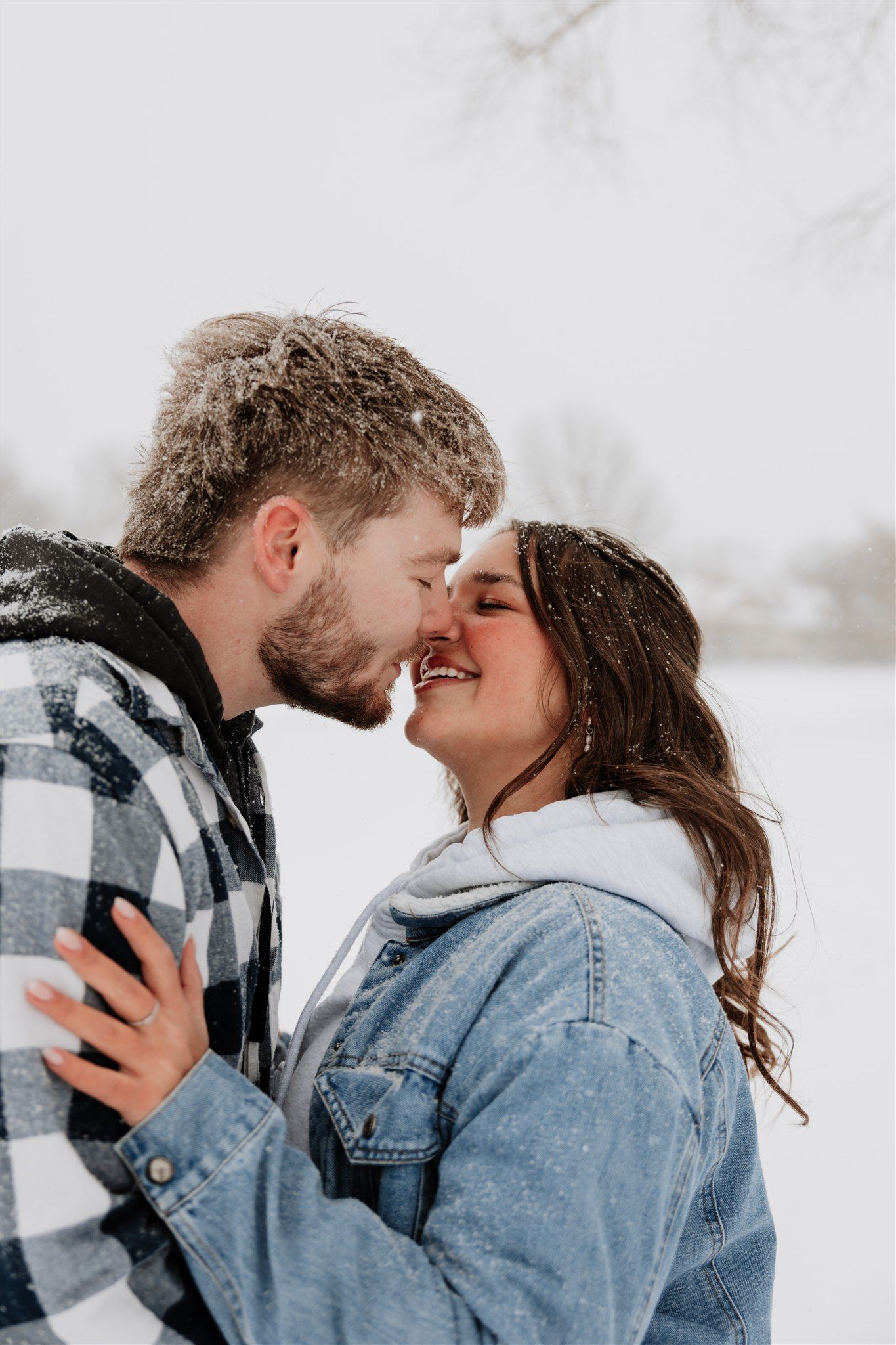 A couple in winter clothing shares an intimate moment in the snow.