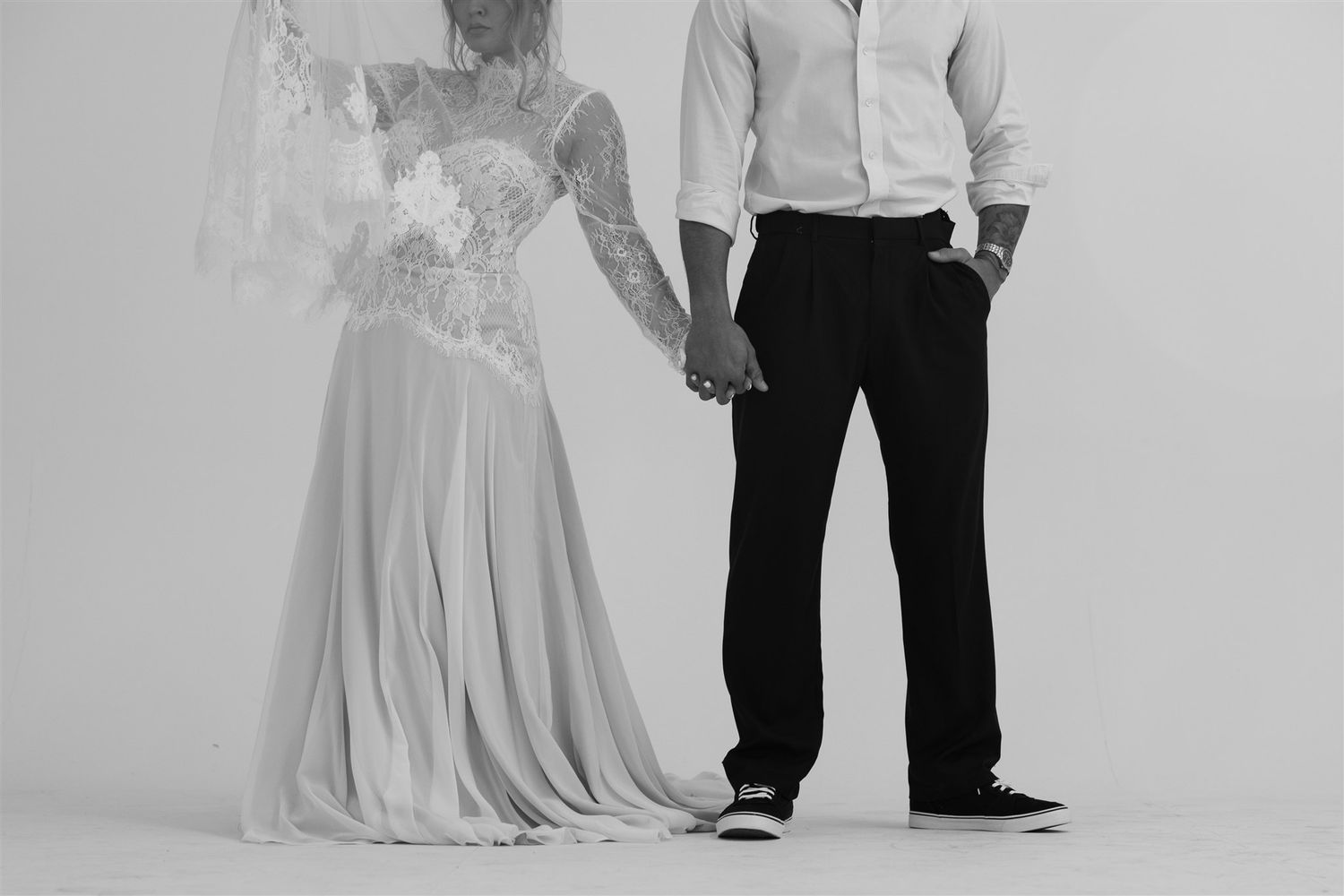Elegant maternity photo session with couple in formal attire against light background.