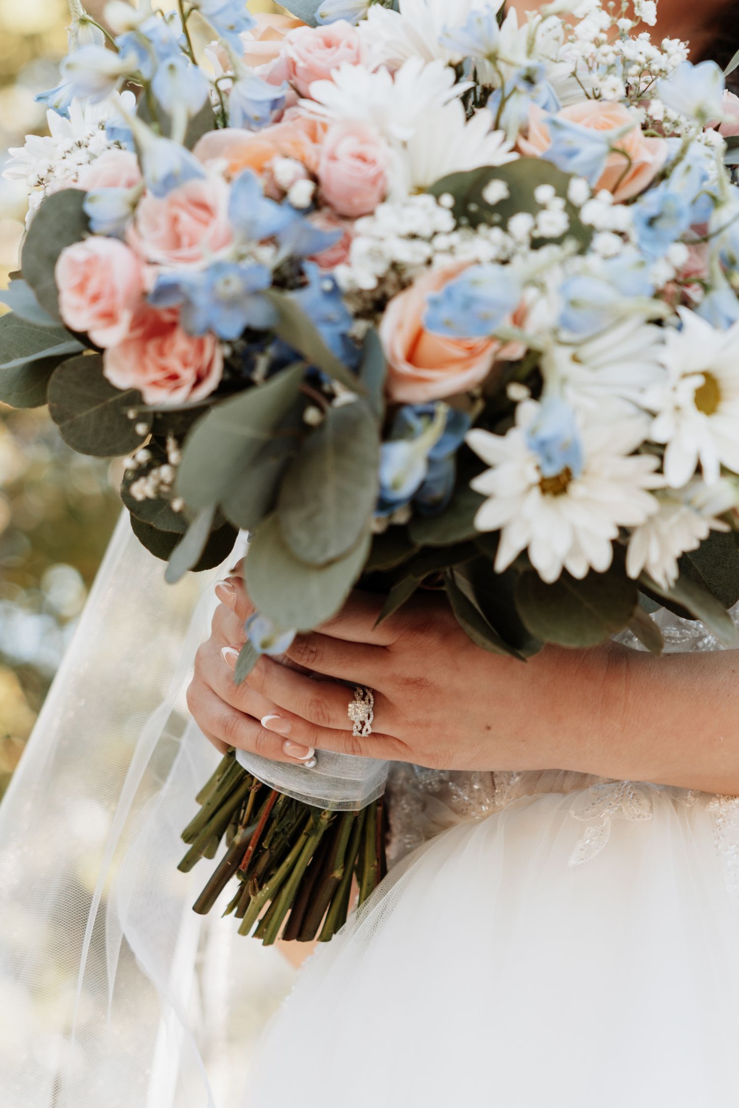 Pastel bridal bouquet with blue and pink flowers, white daisies and eucalyptus.