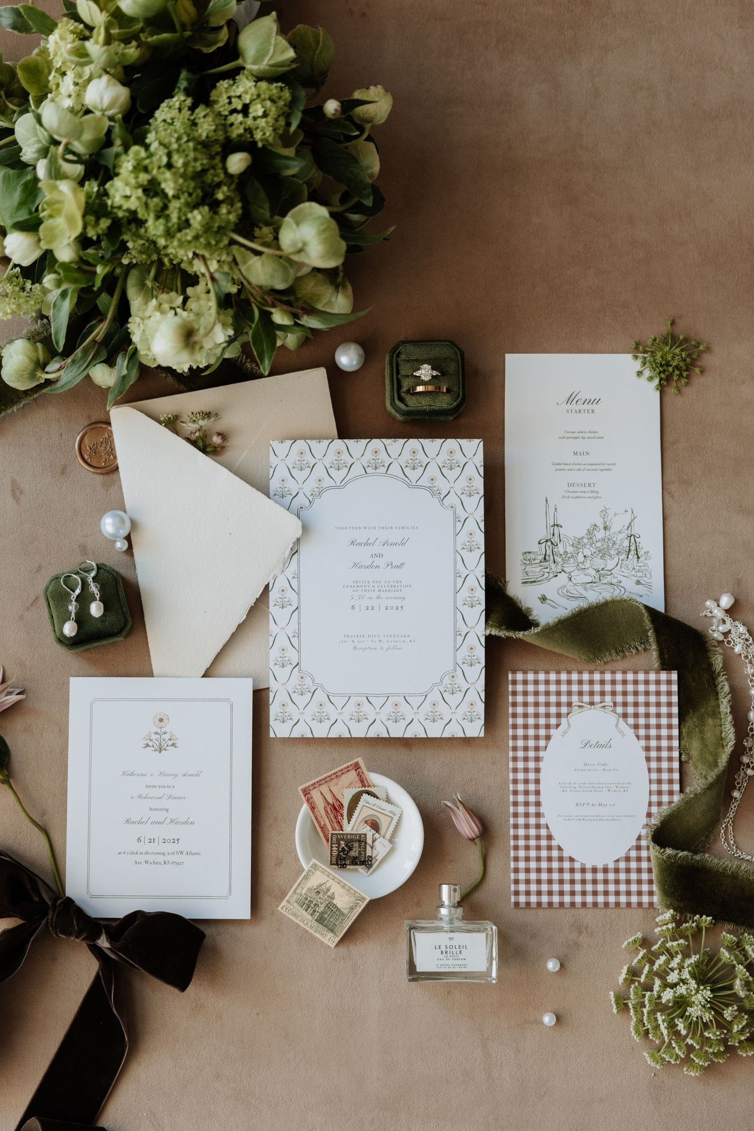 Wedding stationery flat lay with floral arrangements, invitations and decorative elements on brown surface.