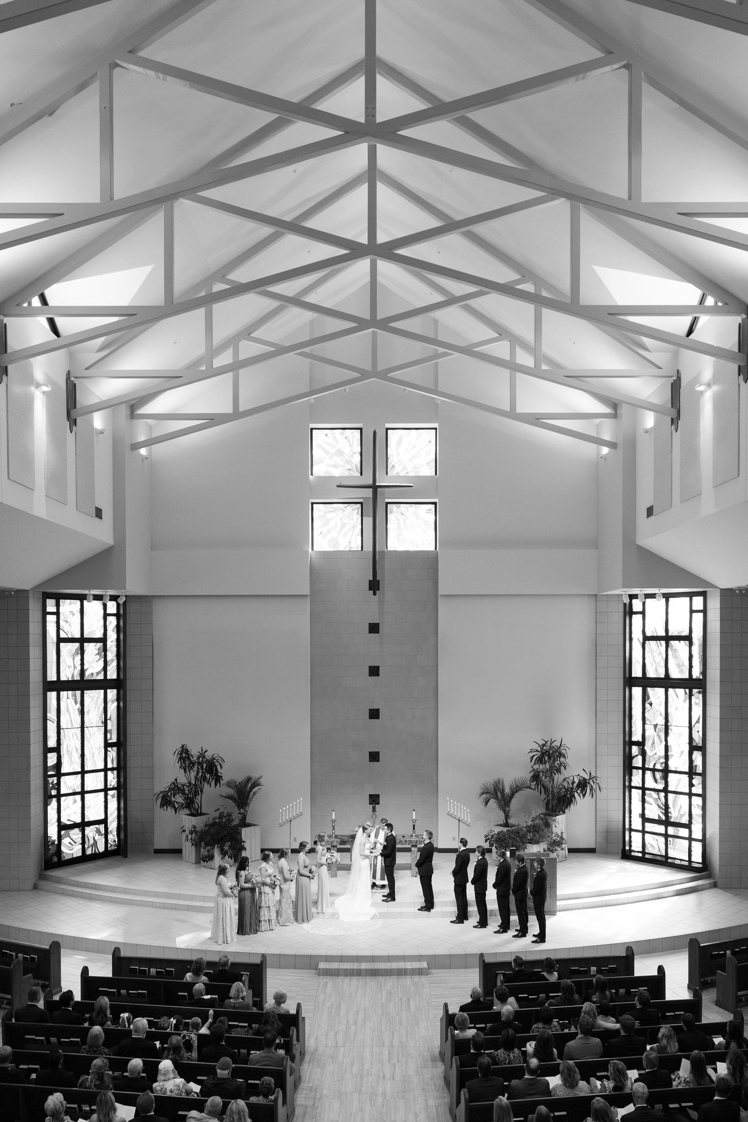 Modern white chapel interior with exposed beams and rows of black chairs set up for ceremony.