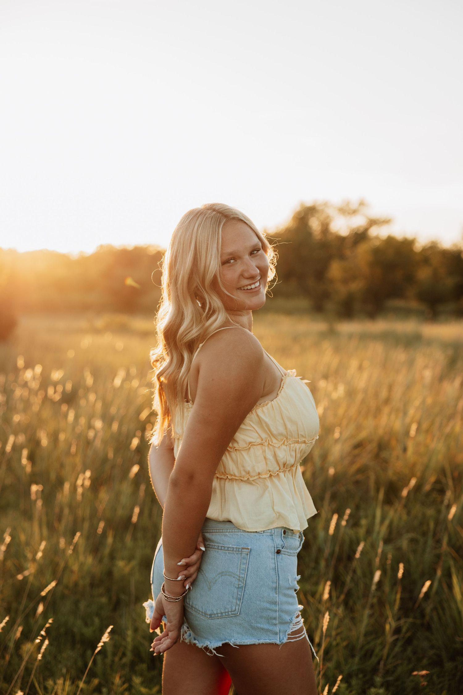 Golden hour portraits in casual summer outfit among tall grass.