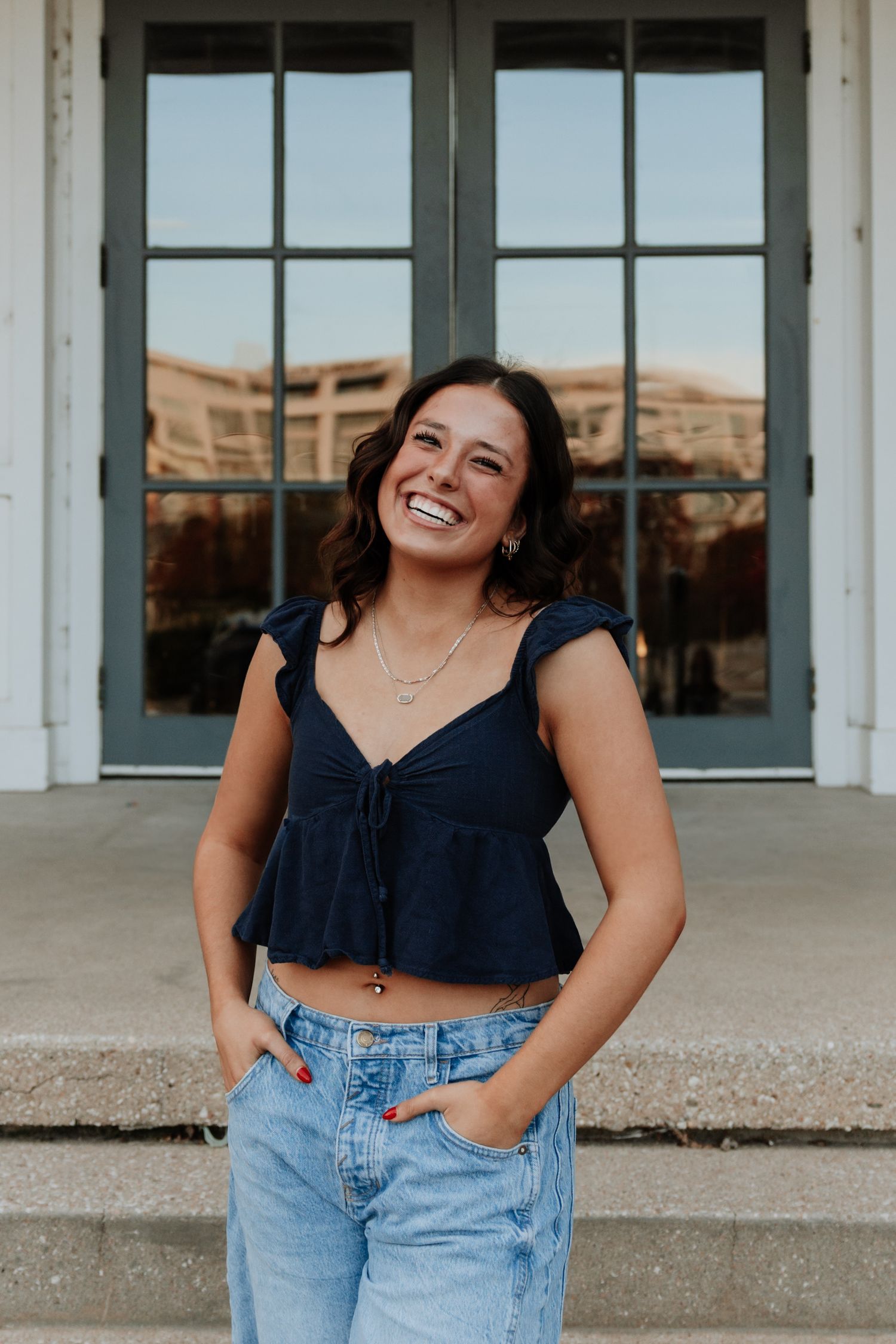 Casual portrait session featuring navy crop top and denim against white building.