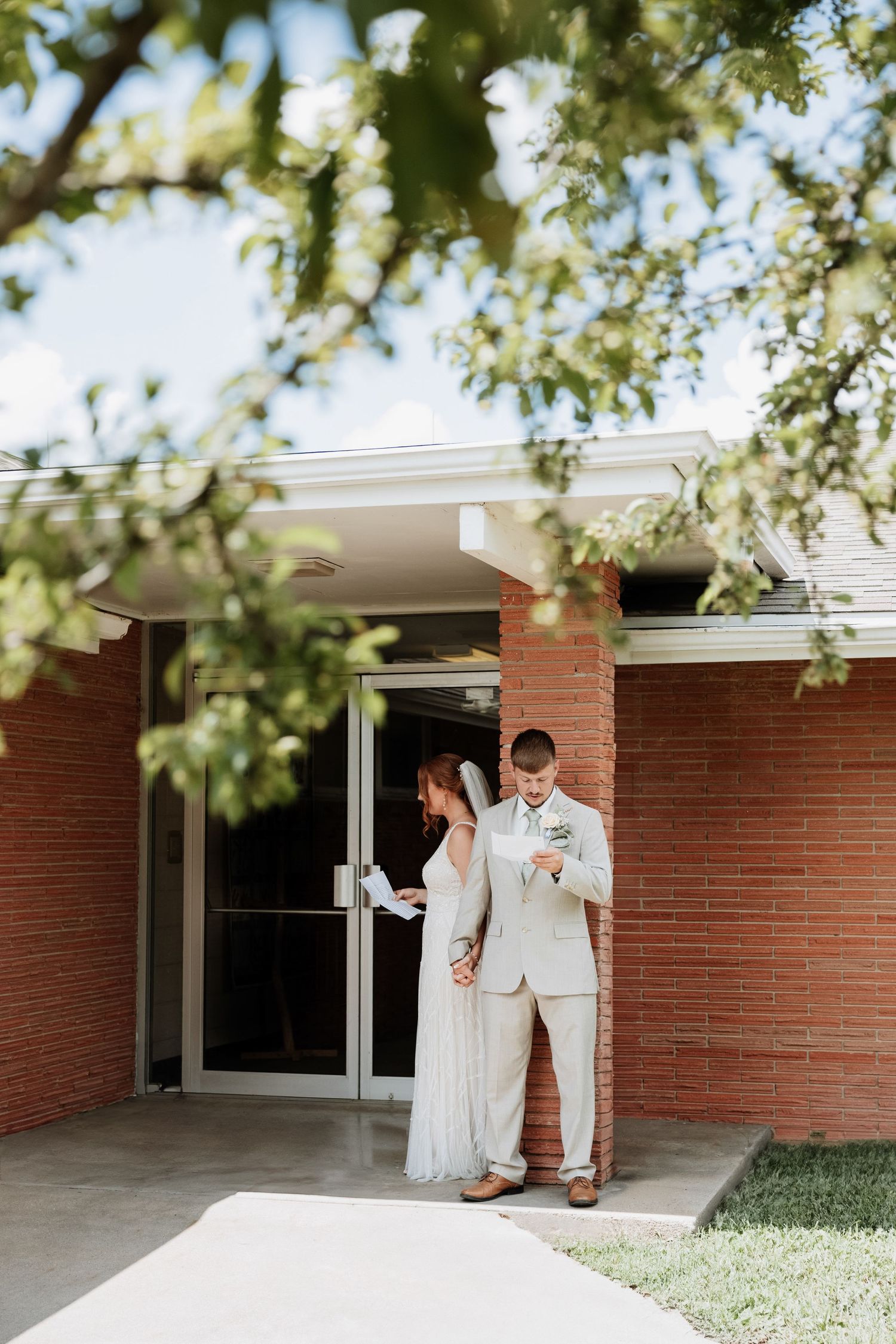 Wedding couple sharing intimate moment against brick building in natural light.