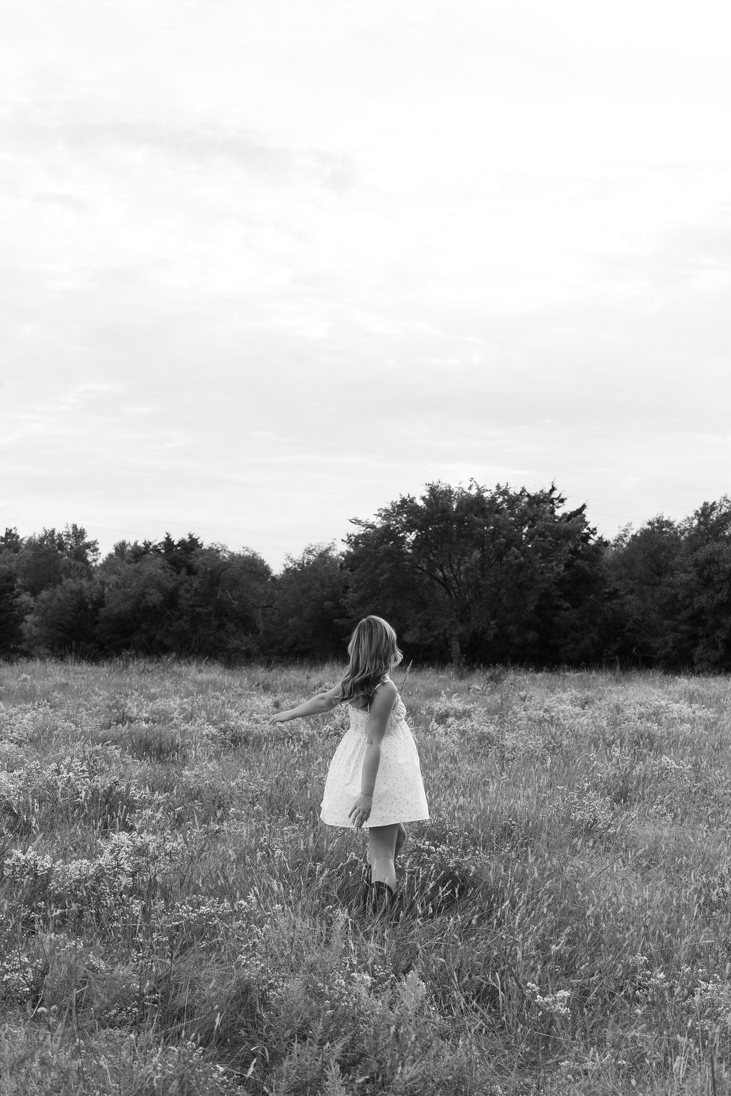 Black and white photos of figure walking through meadow landscape.