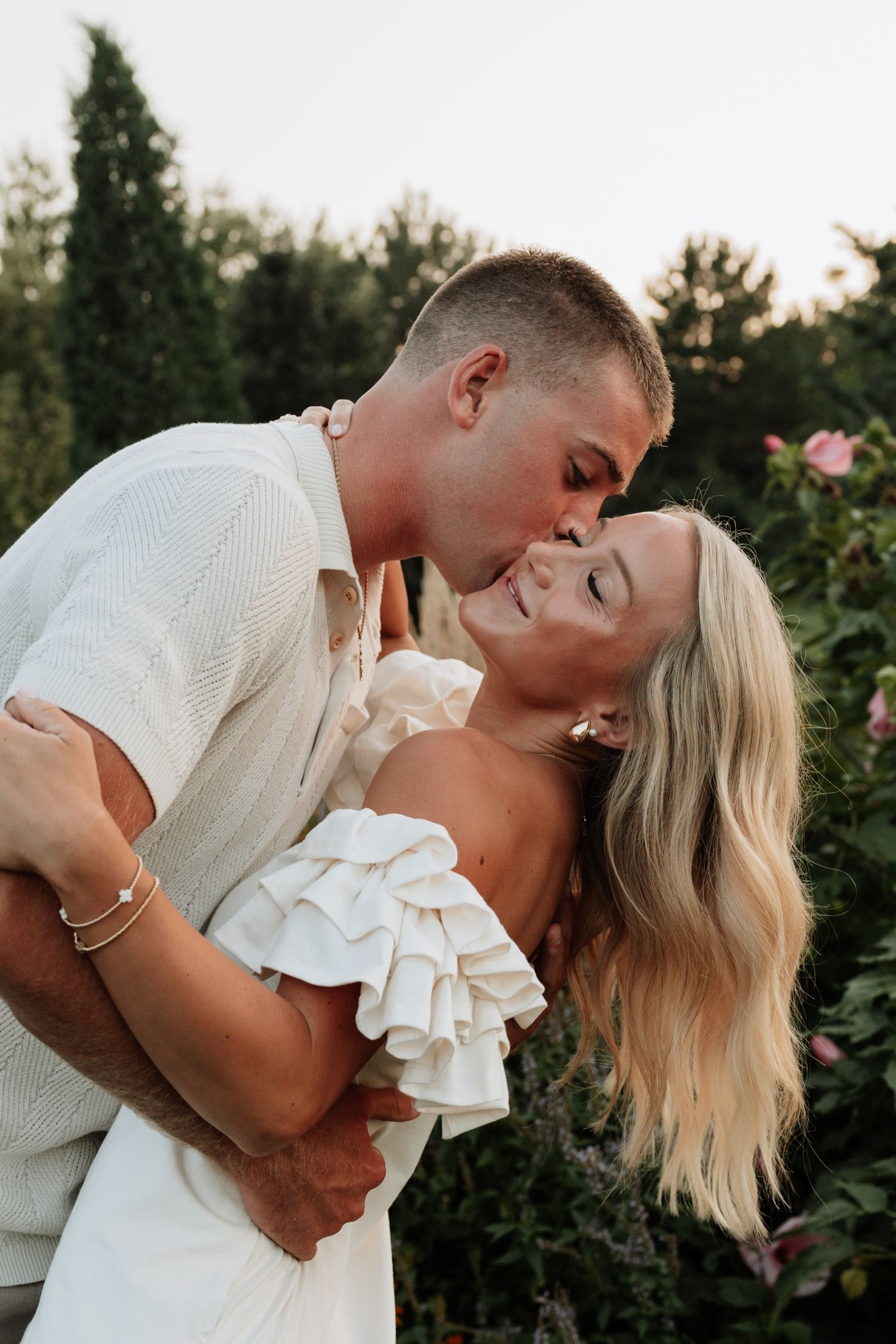 Romantic couple embracing in a garden setting during golden hour.
