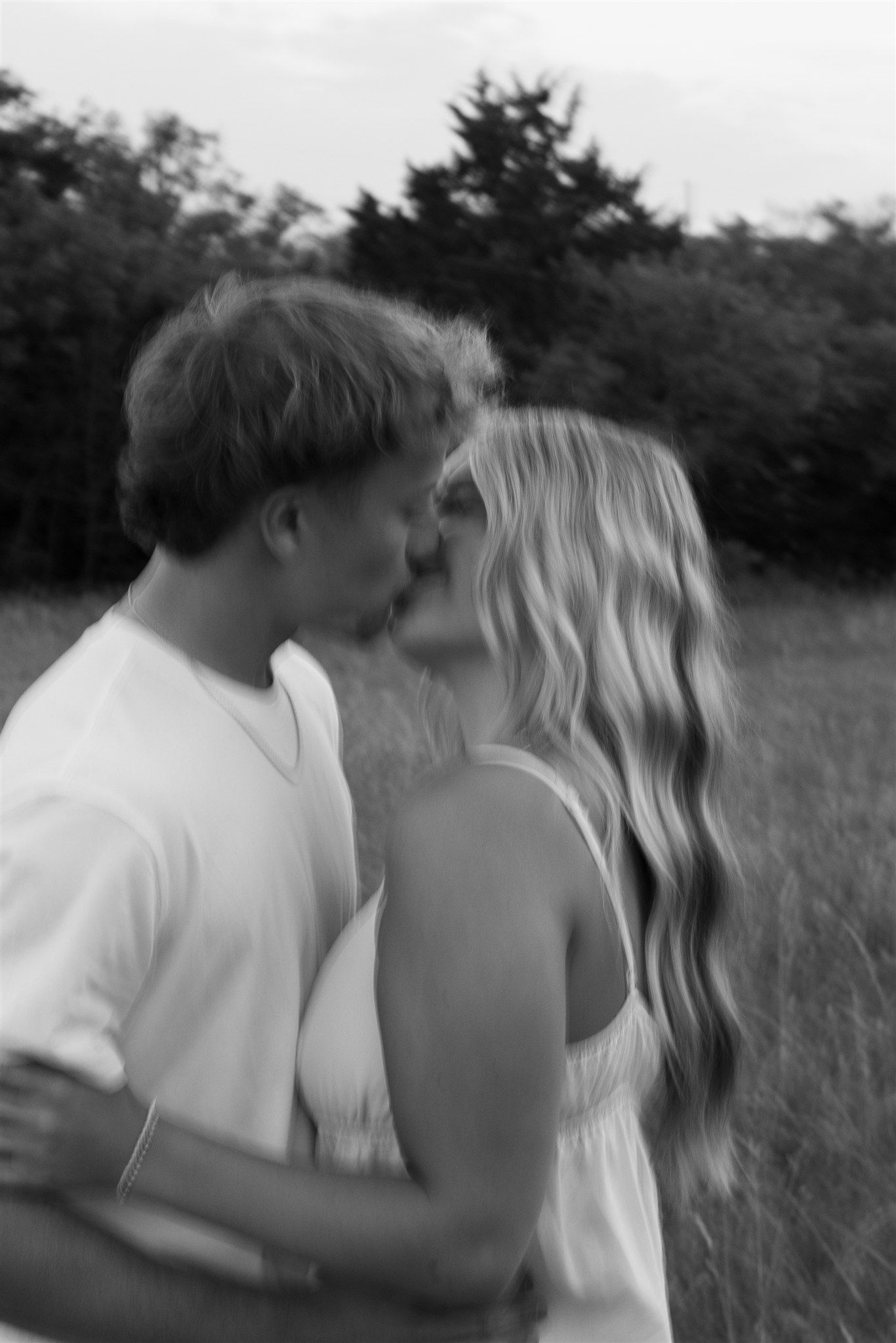 Romantic black and white couple portrait in tall grass field.