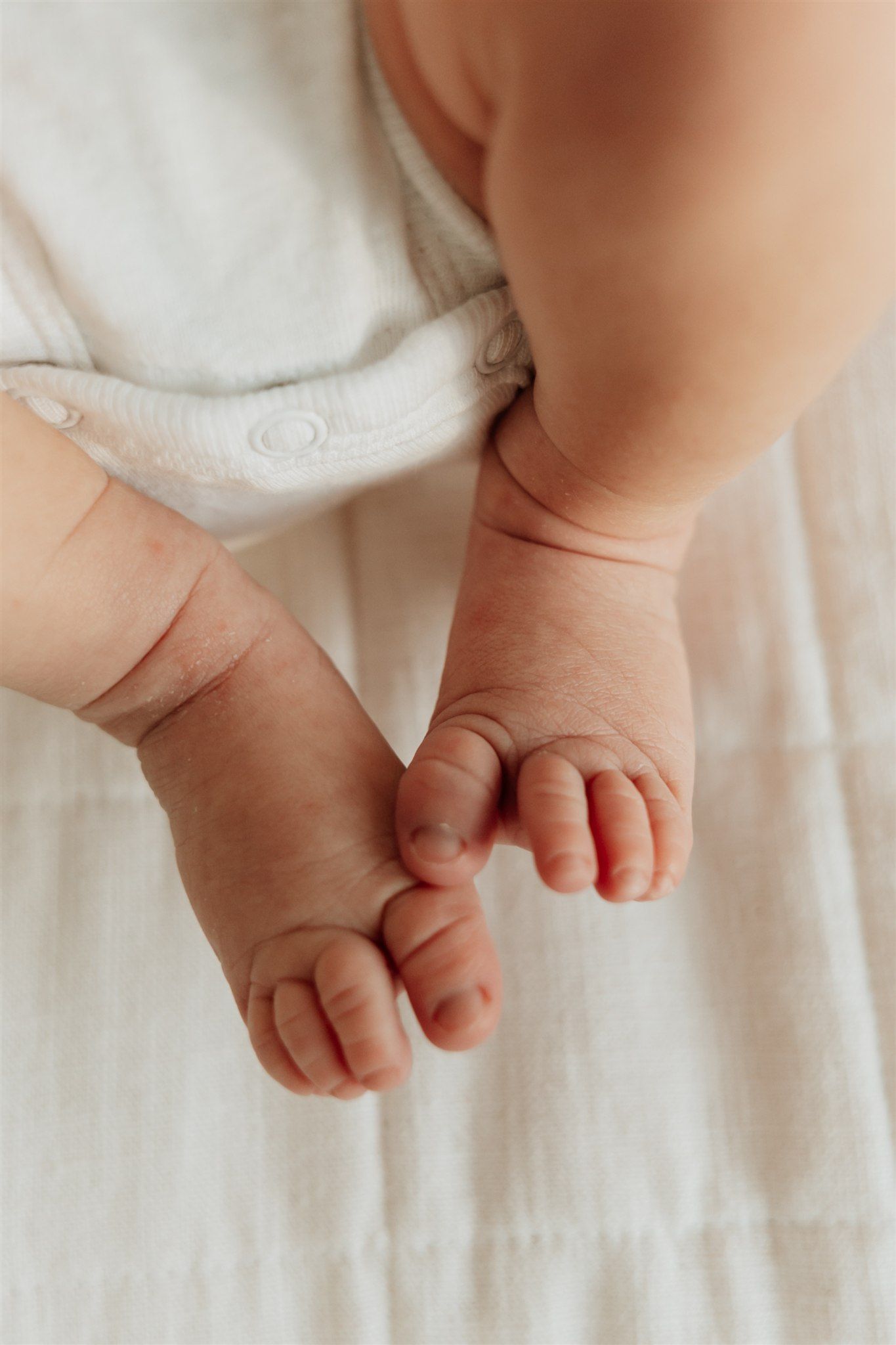 Close up photograph of tiny baby feet on white bedding.