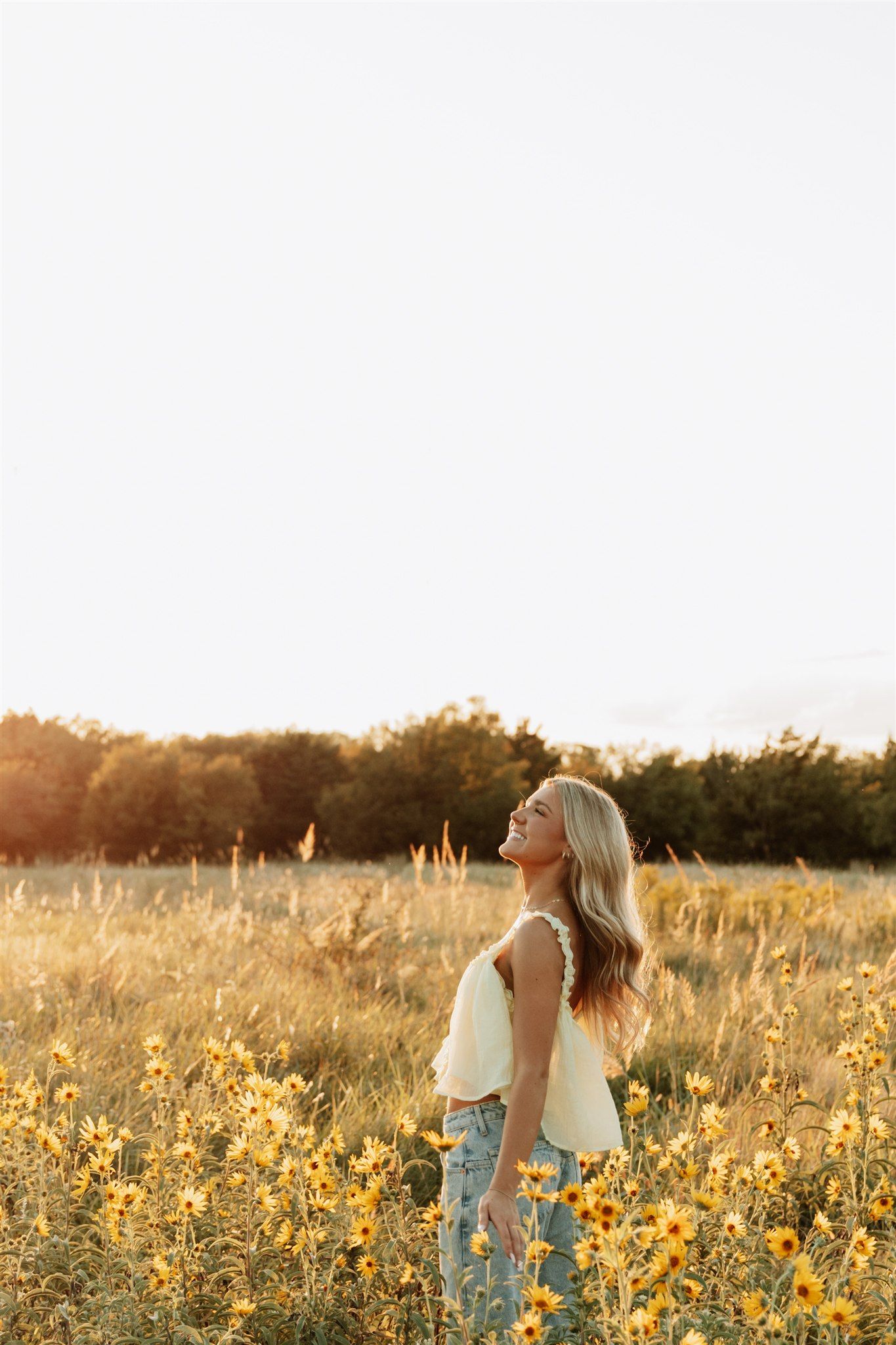 Family walking through sunlit field of yellow wildflowers at golden hour.