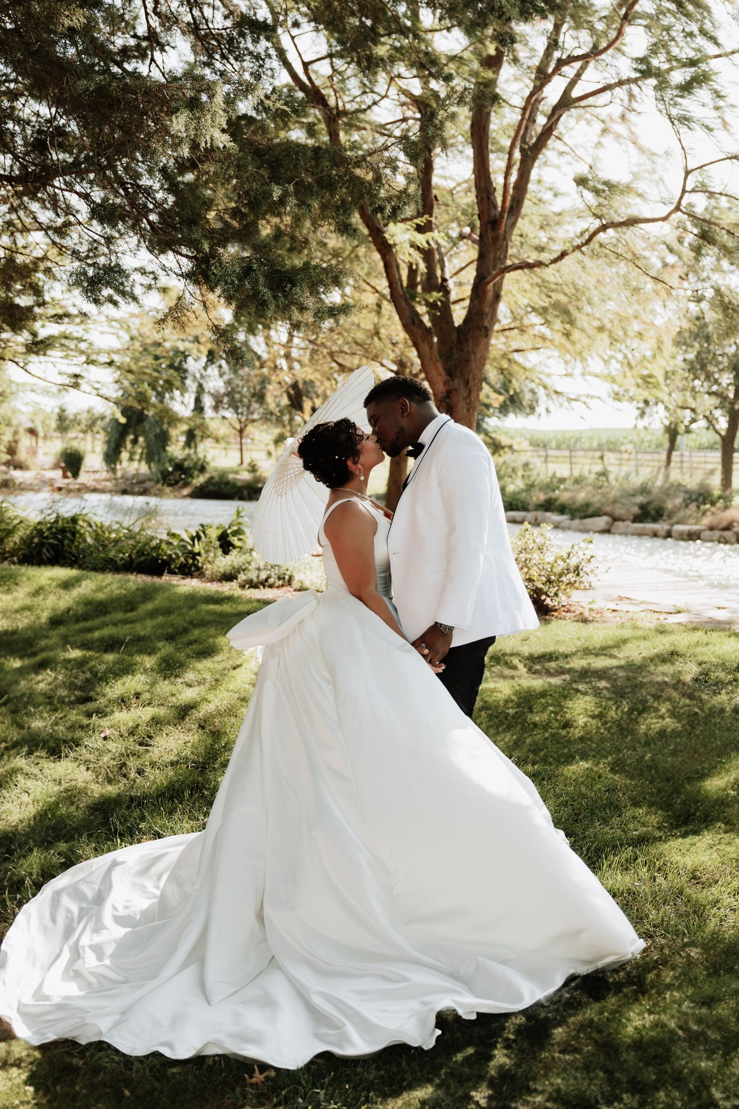 Romantic wedding portraits in sunlit garden with flowing white dress.