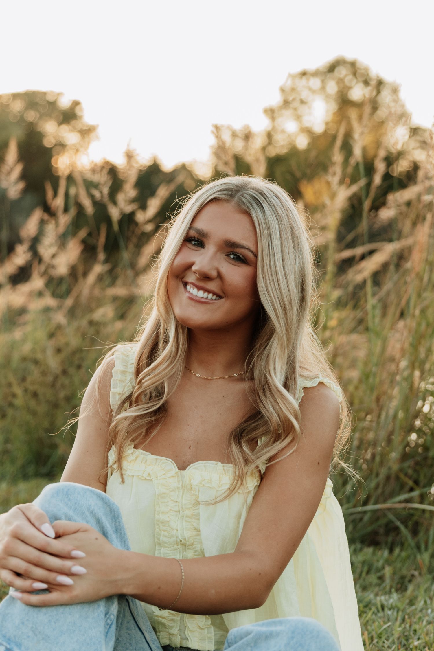 Natural outdoor portrait session in tall grass during golden hour.