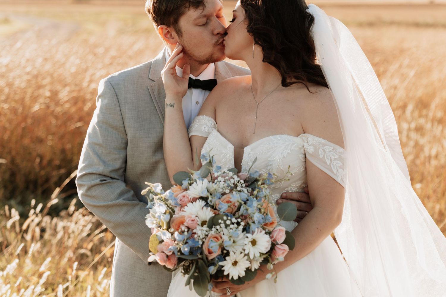 Romantic wedding couple embracing in golden wheat field at sunset.