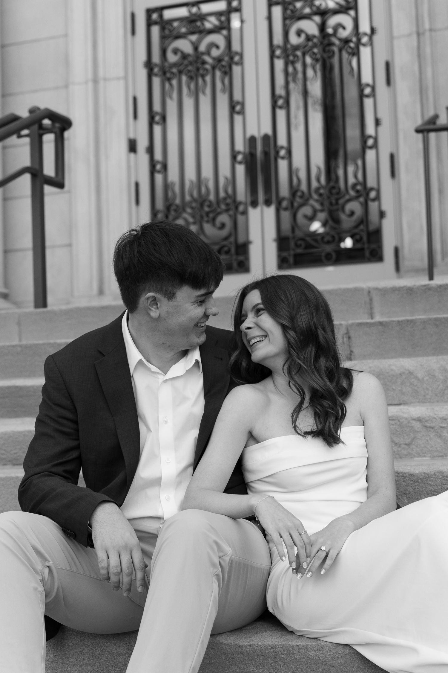 Elegant couple in white attire sharing romantic moments on ornate steps.