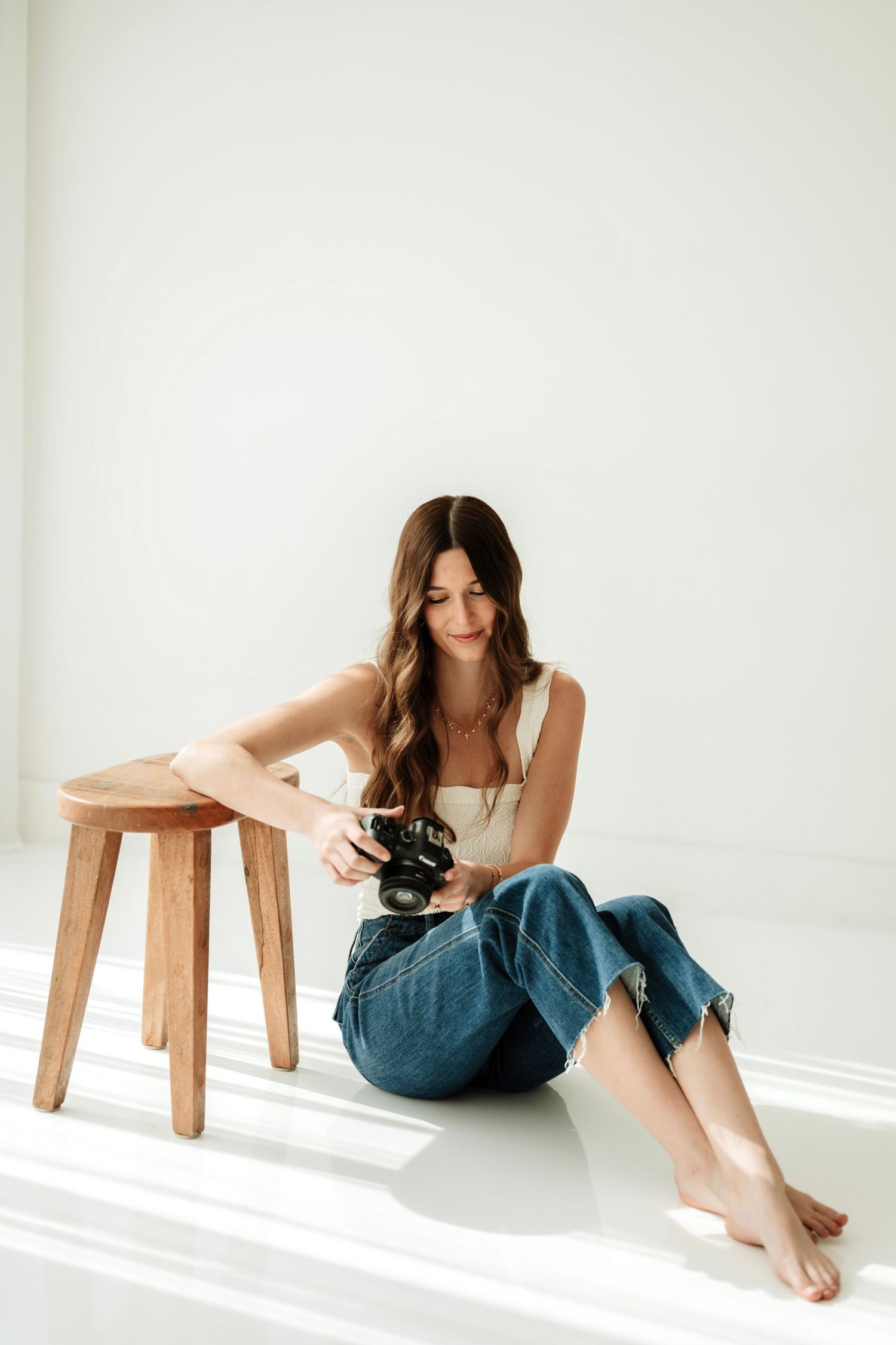 Minimalist portrait series with wooden stool and white backdrop.