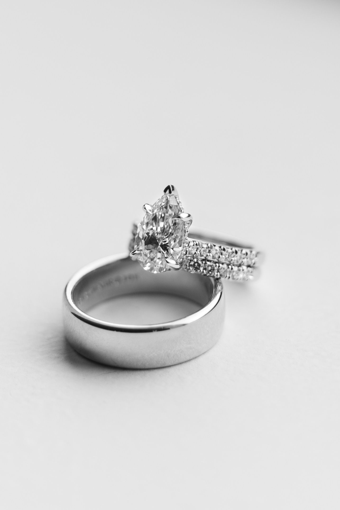 Wedding rings and engagement ring with diamond details on white background.