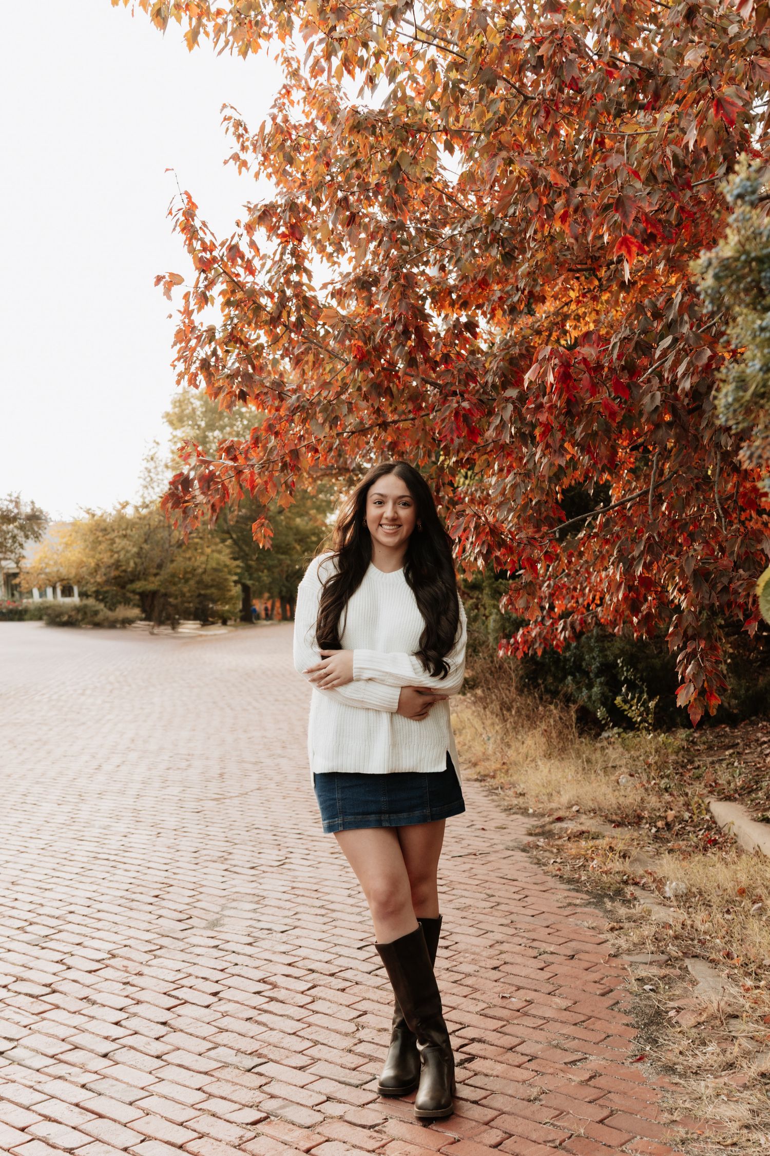 Fall fashion photoshoot on brick pathway with autumn foliage.