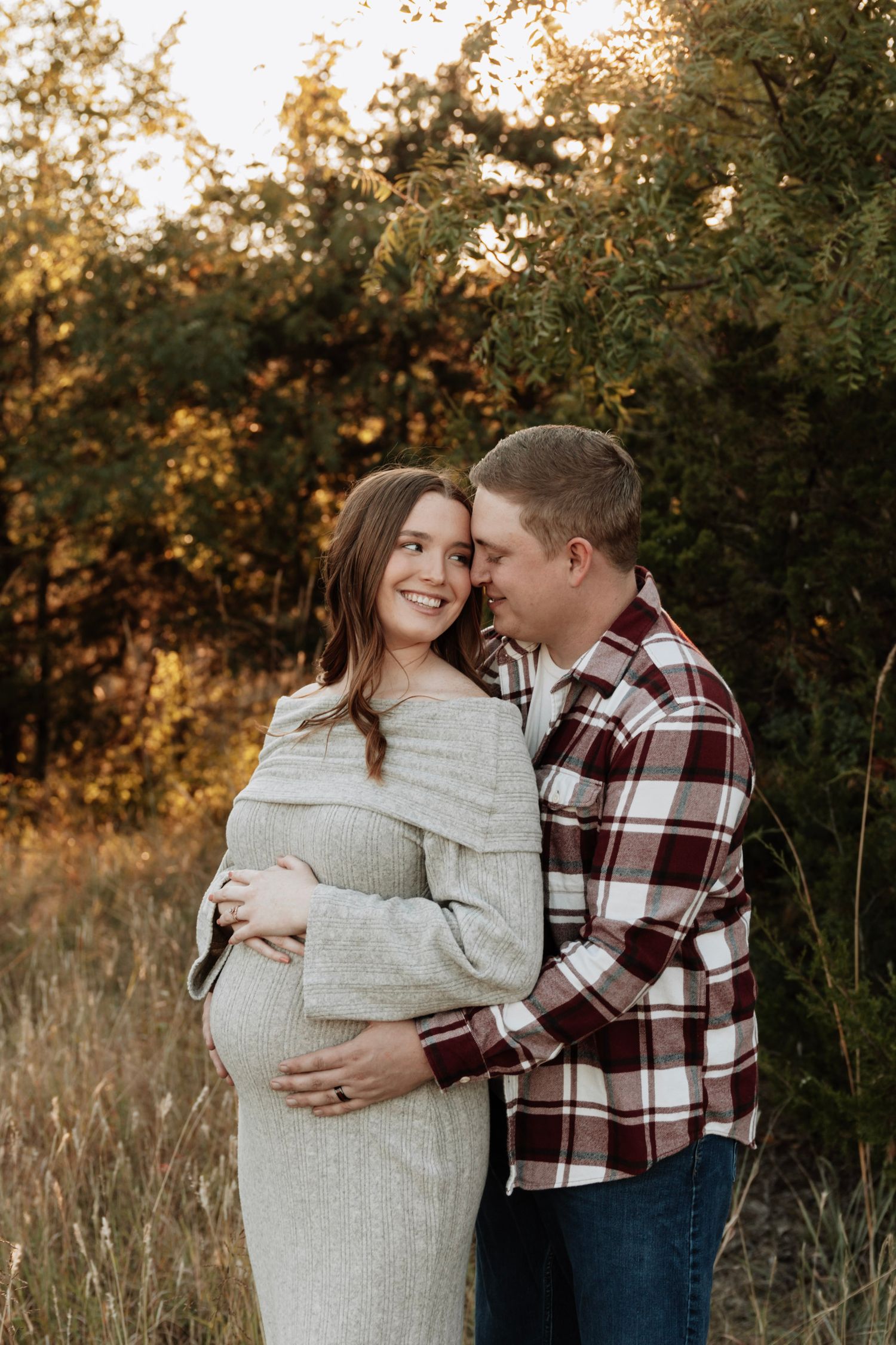 A couple poses together during sunset, celebrating an upcoming arrival.