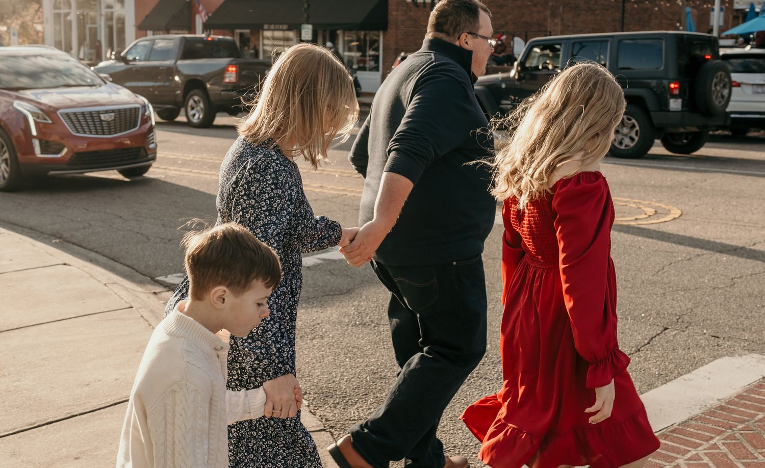 People in formal attire walking together on a city street during an outdoor event.