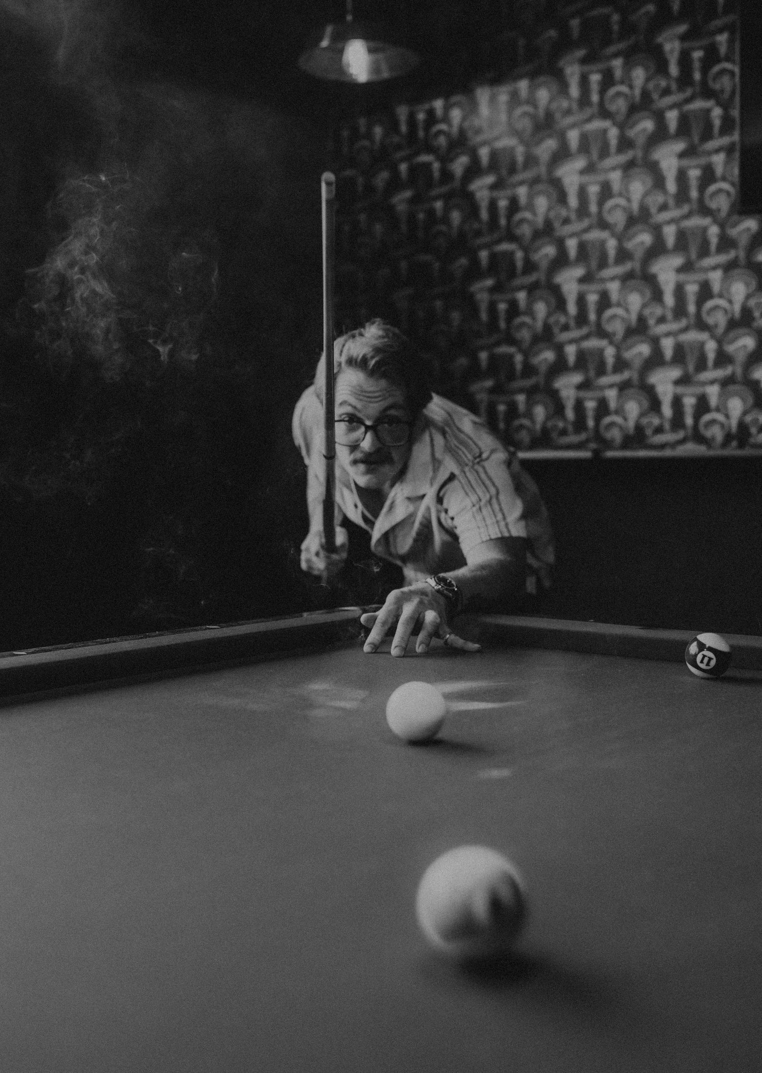 A sequence of black and white photos showing a billiards player lining up and making a shot on a pool table.