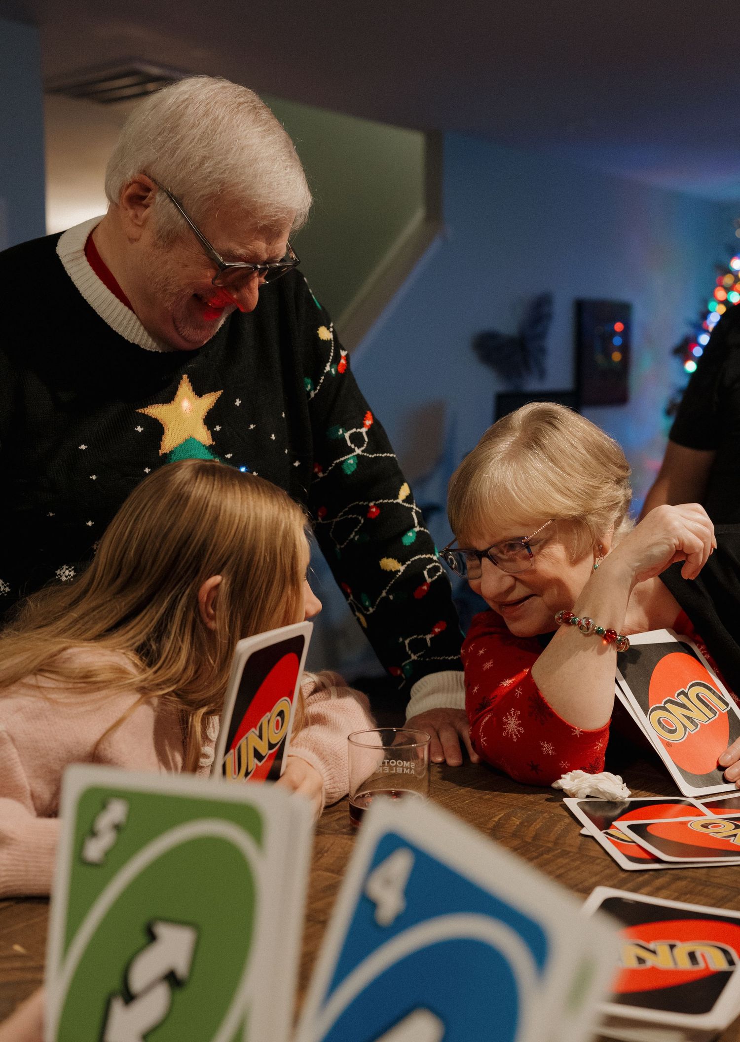 People gathered around a table engaged in a holiday craft activity with colorful cards and decorations.